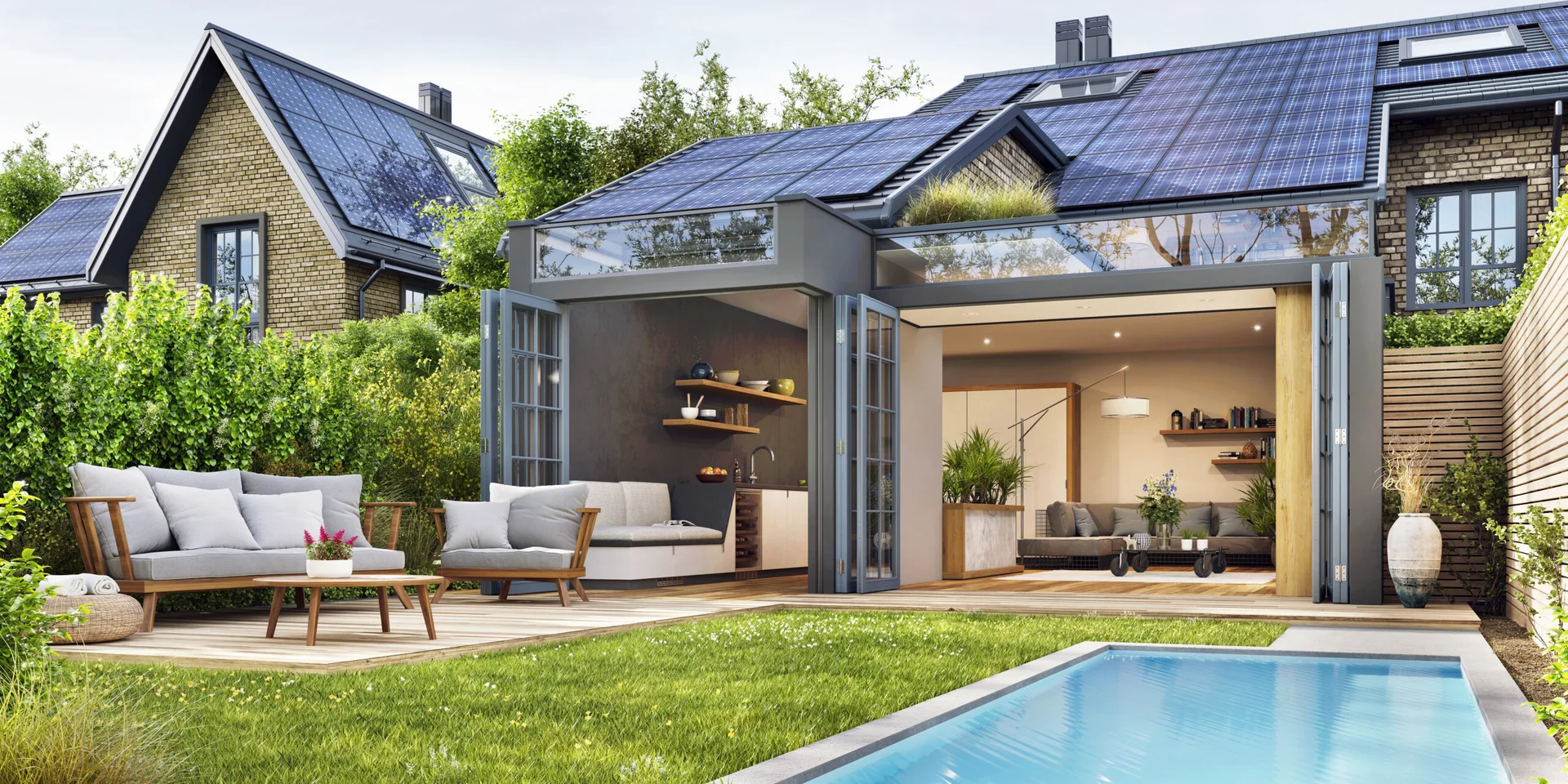 A modern backyard patio features a wooden deck with gray sofas, a swimming pool, and folding glass doors opening to an indoor kitchen.