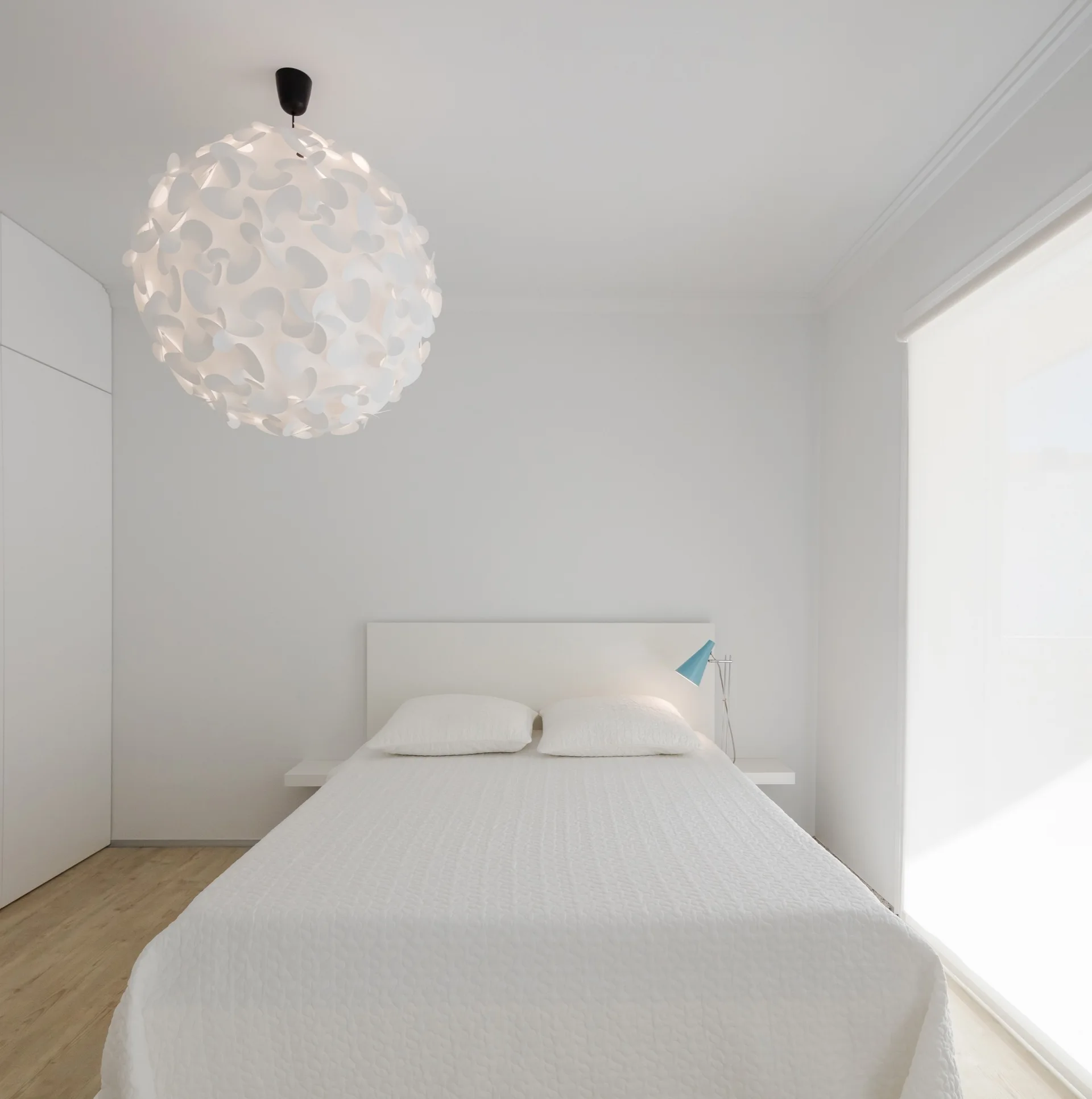 A minimalist white bedroom features a bed with matching white bedding, a large spherical pendant light, a small blue reading lamp, and light wood floors.
