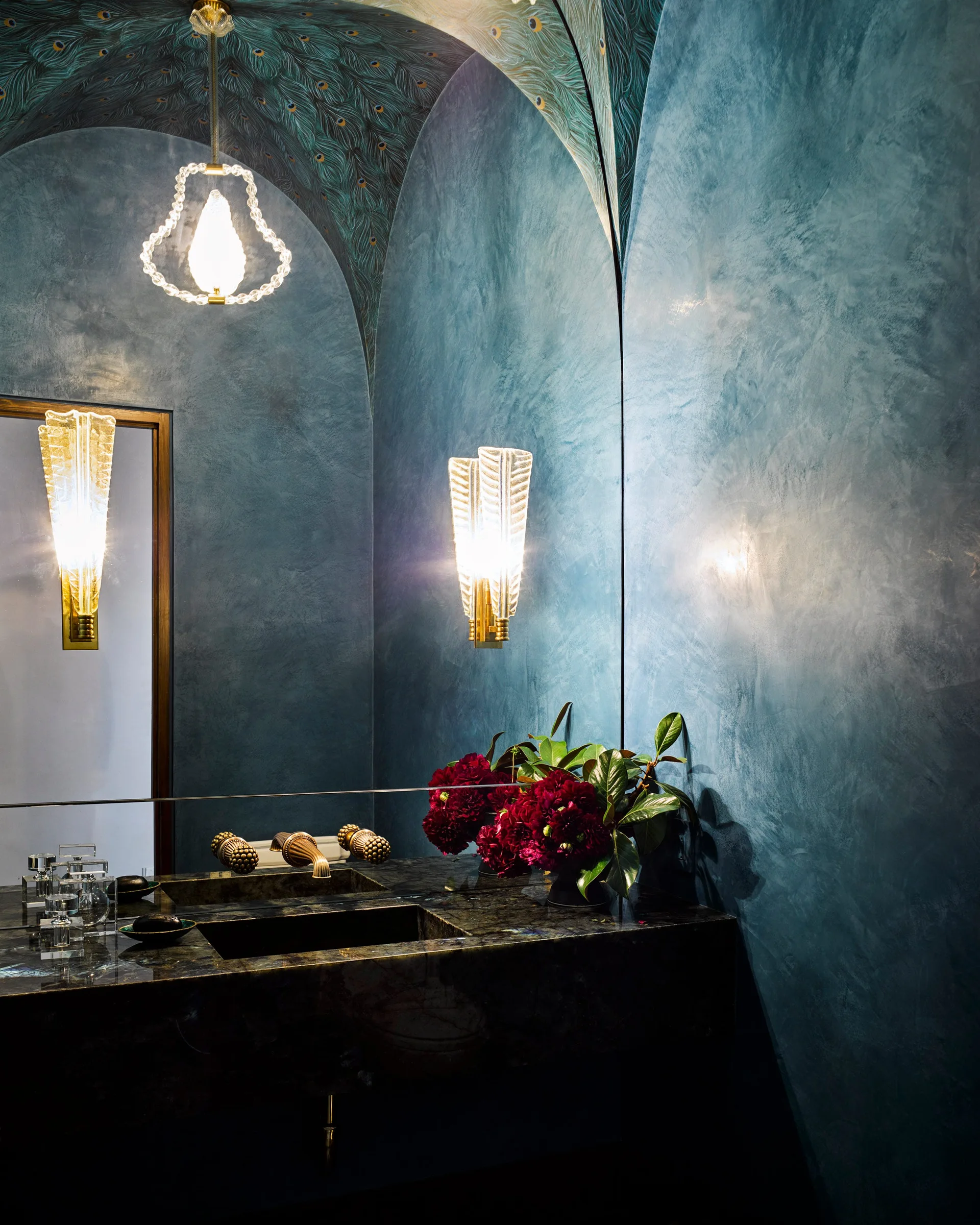 A blue powder room features a textured wall finish, a peacock-patterned arched ceiling, and a dark veined stone vanity.