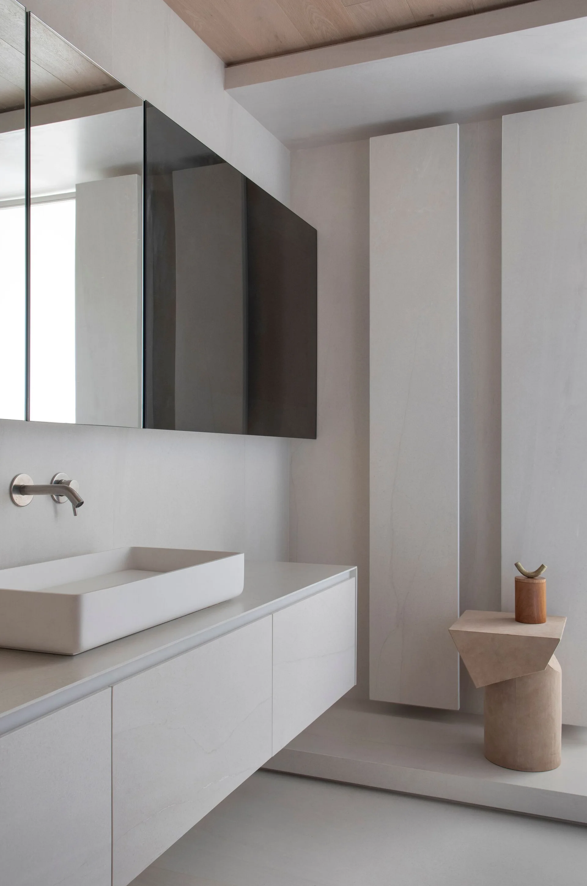 A modern bathroom showcases a floating off-white vanity with a rectangular vessel sink, a wall-mounted faucet, and vertical stone-like wall panels.