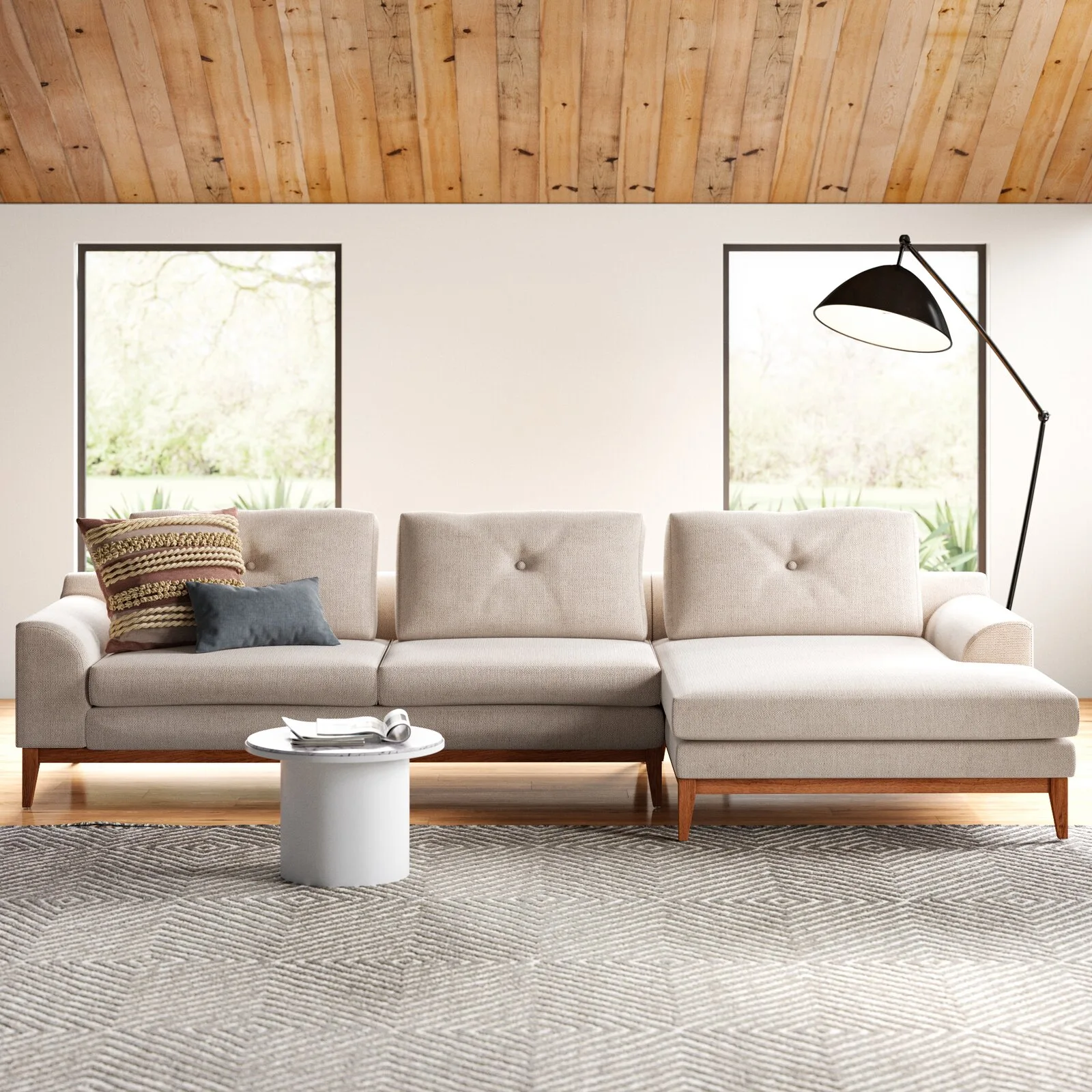 A modern living room features a beige sectional sofa under a sloped wood plank ceiling, styled with a geometric rug and a black floor lamp.
