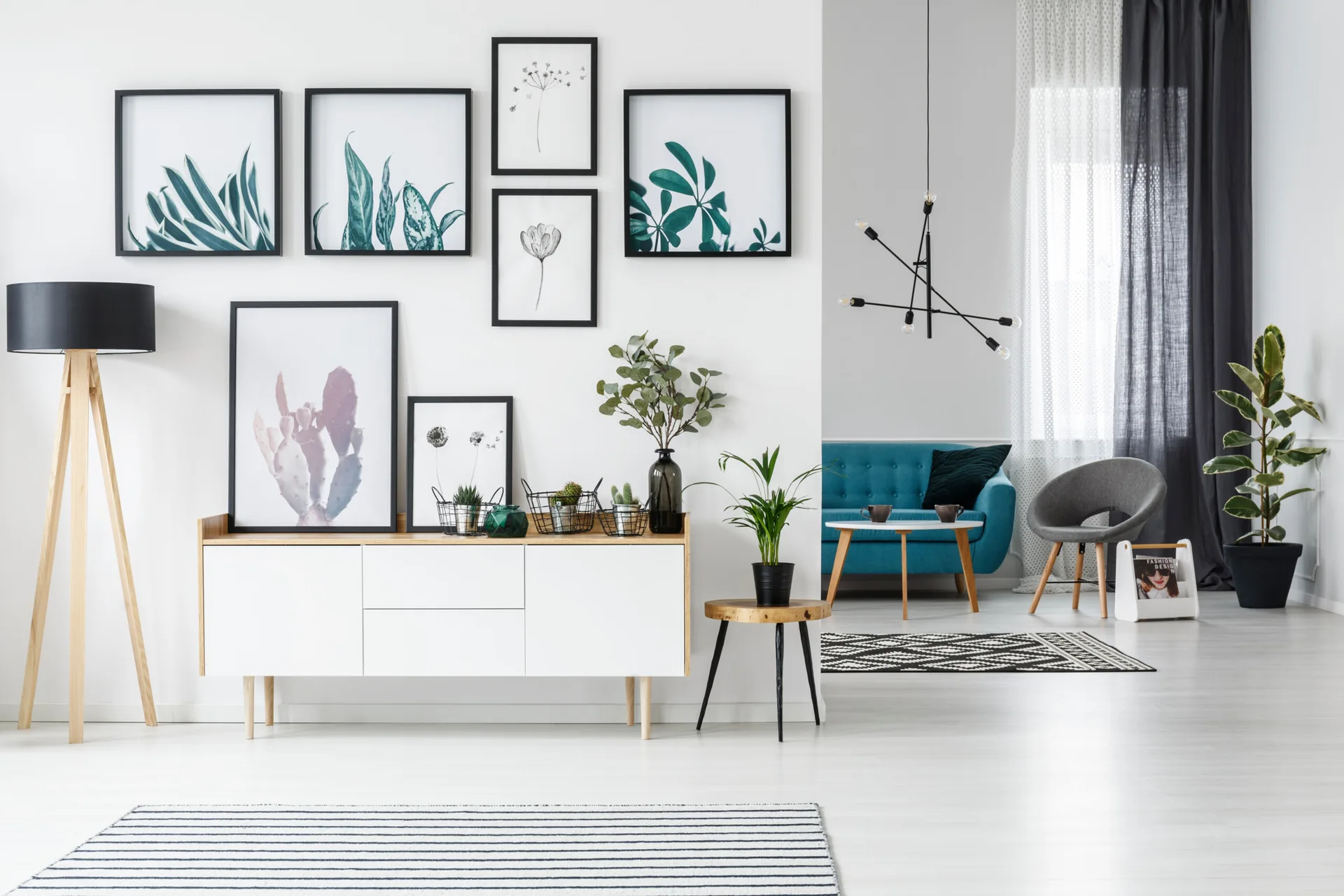 A bright Scandinavian living room featuring a white and wood sideboard beneath a botanical gallery wall, with a turquoise sofa visible in the background.