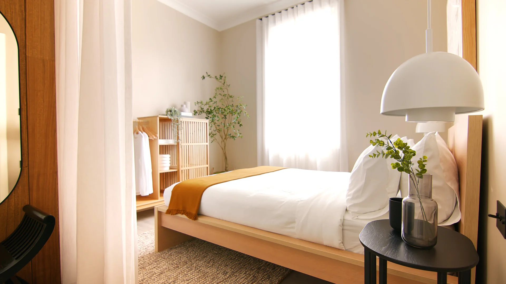 A minimalist bedroom features a light wood platform bed, a slatted wooden wardrobe, and a white dome pendant light over a black side table.