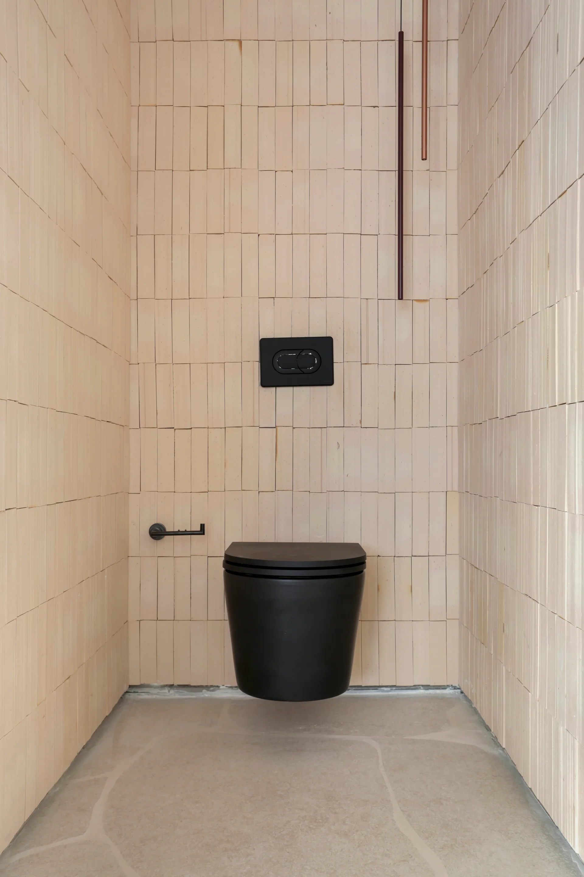 A minimalist powder room featuring walls clad in vertical beige tiles, a wall-mounted matte black toilet, and matching black hardware.