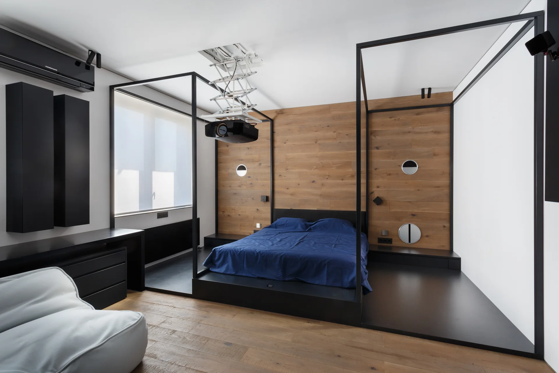 A modern minimalist bedroom featuring a black metal canopy platform bed and a natural wood plank accent wall.
