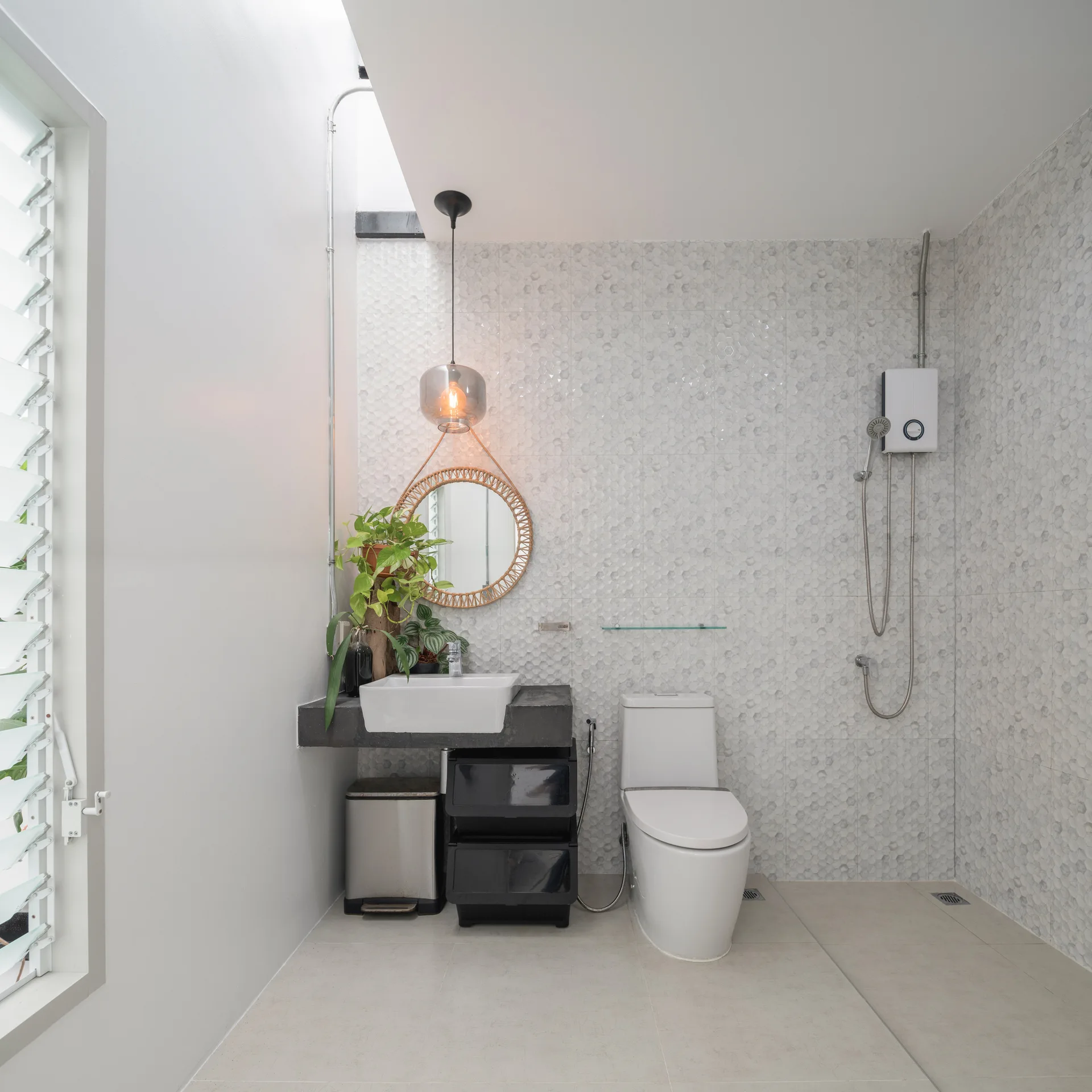 A minimalist bathroom features a floating black vanity with a vessel sink, white hexagonal wall tiles, and a round woven mirror.