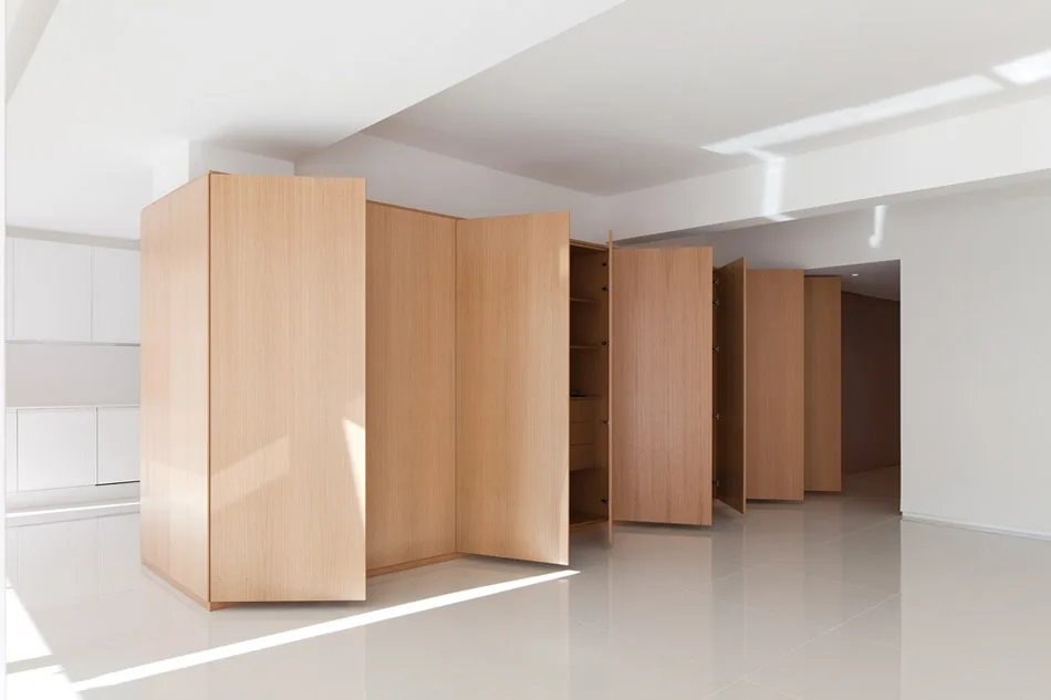 A large light wood veneer cabinetry unit with open doors stands on a reflective white tile floor against plain white walls.