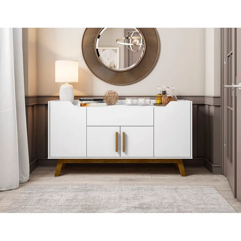 A white sideboard with wooden legs sits against taupe wainscoting beneath a round ribbed mirror and beside a textured white table lamp.