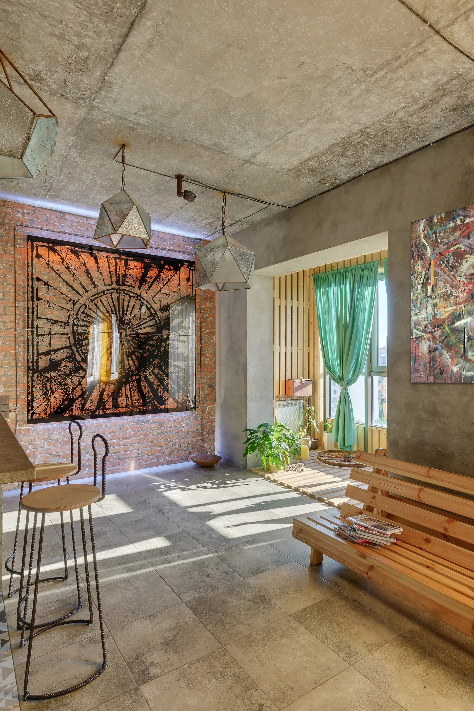 An industrial living room features a raw concrete ceiling, an exposed red brick wall with backlit art, a wood bench, and gray tile flooring.