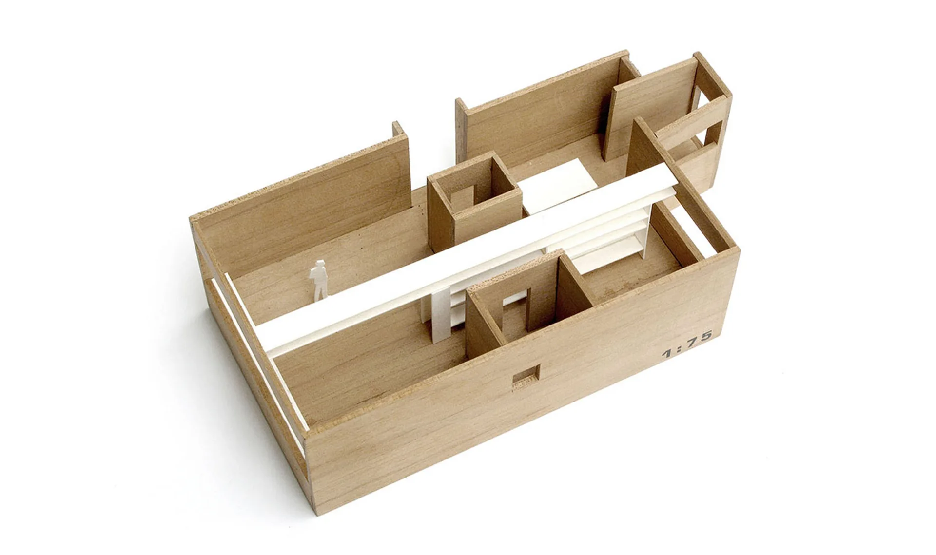 A wooden architectural scale model of an apartment interior layout featuring a central white partition wall and a small white figure.