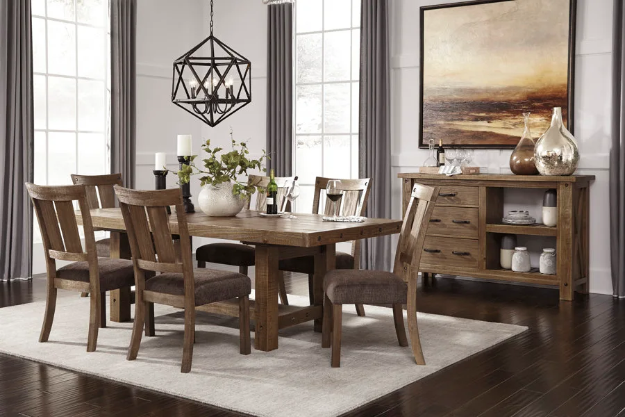 A rustic wooden dining table and matching chairs sit on a light grey rug under a black geometric chandelier next to a wood sideboard.