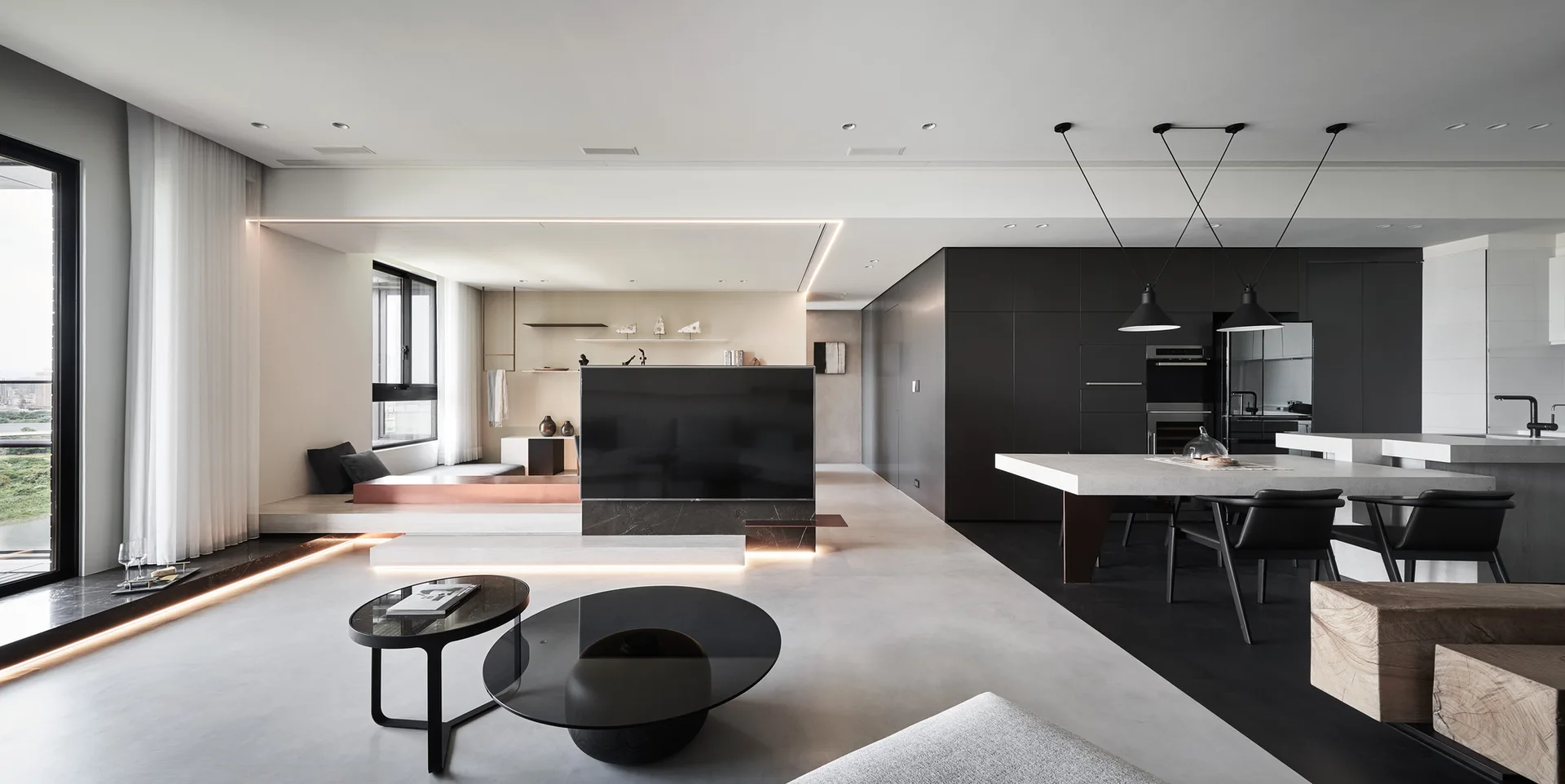 A minimalist open-plan living and dining area features a central television partition, a raised platform with LED strip lights, and matte black cabinetry.