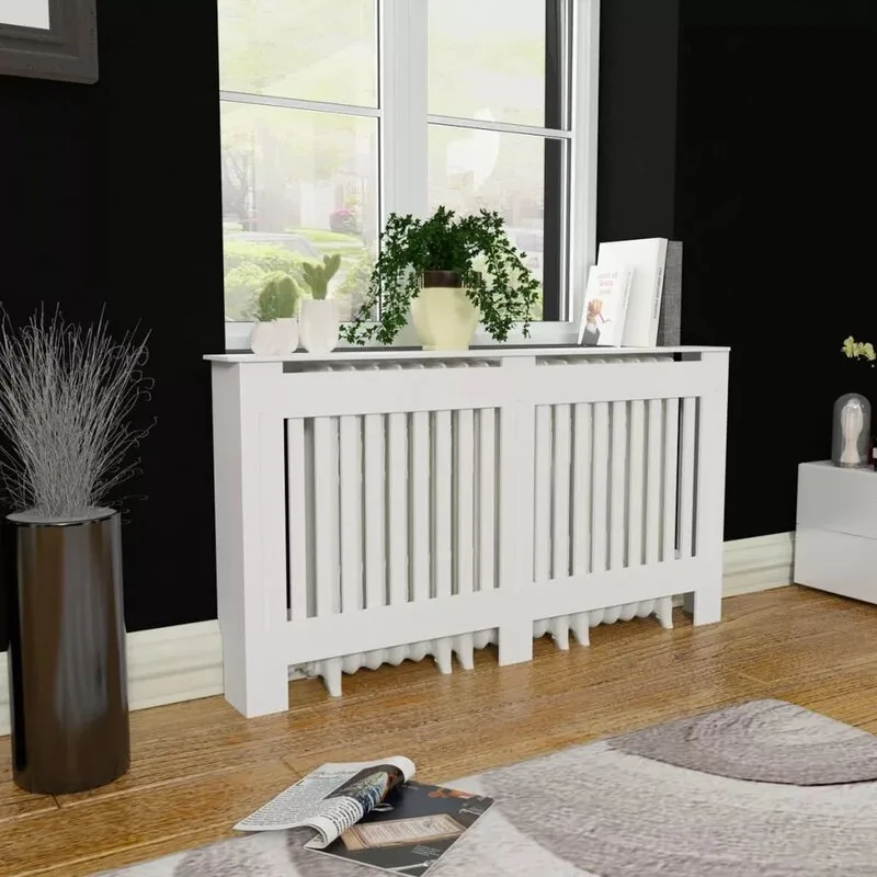 A white wooden slatted radiator cover stands against a black wall beneath a window, holding potted plants and books on a wood floor.