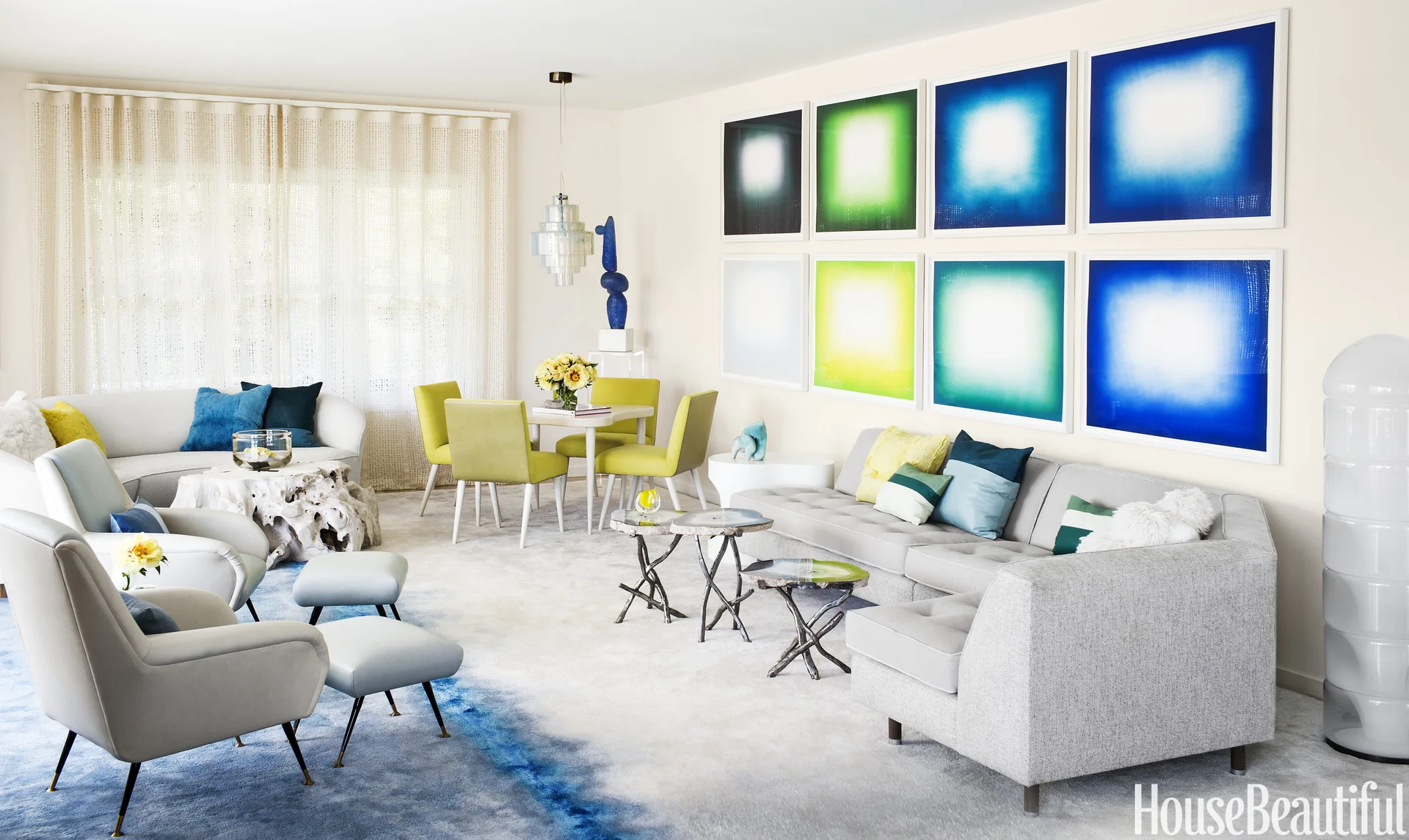 A modern open living space featuring a grey sectional sofa, an eight-frame colorful grid gallery wall, and a blue gradient area rug.
