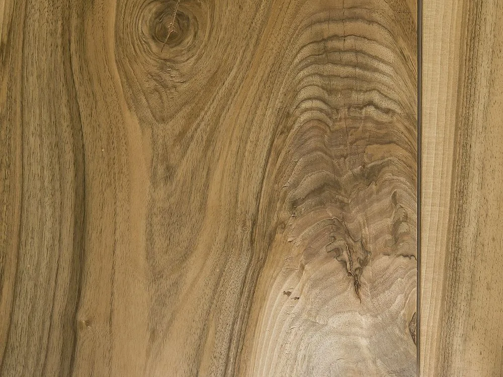 A close-up view of a warm brown wood surface highlighting its natural grain patterns and a prominent knot.