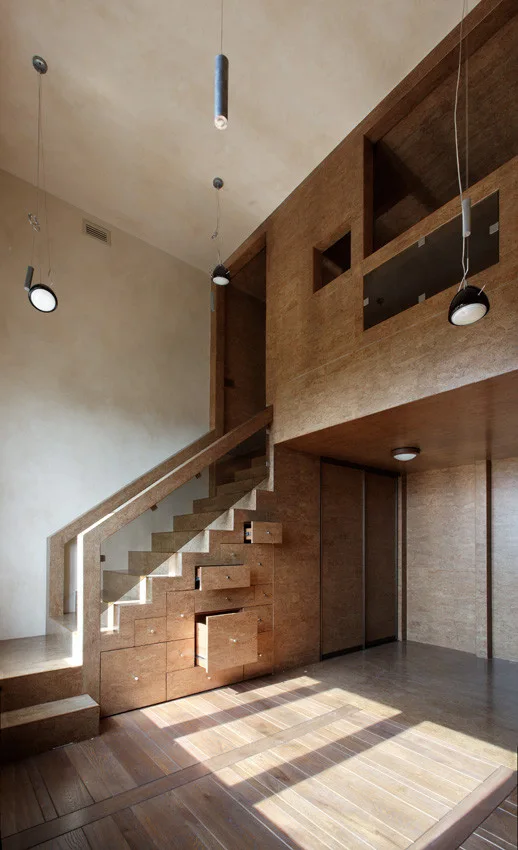 A modern wooden staircase with glass railings features several open built-in drawers integrated directly into its stepped side panel.