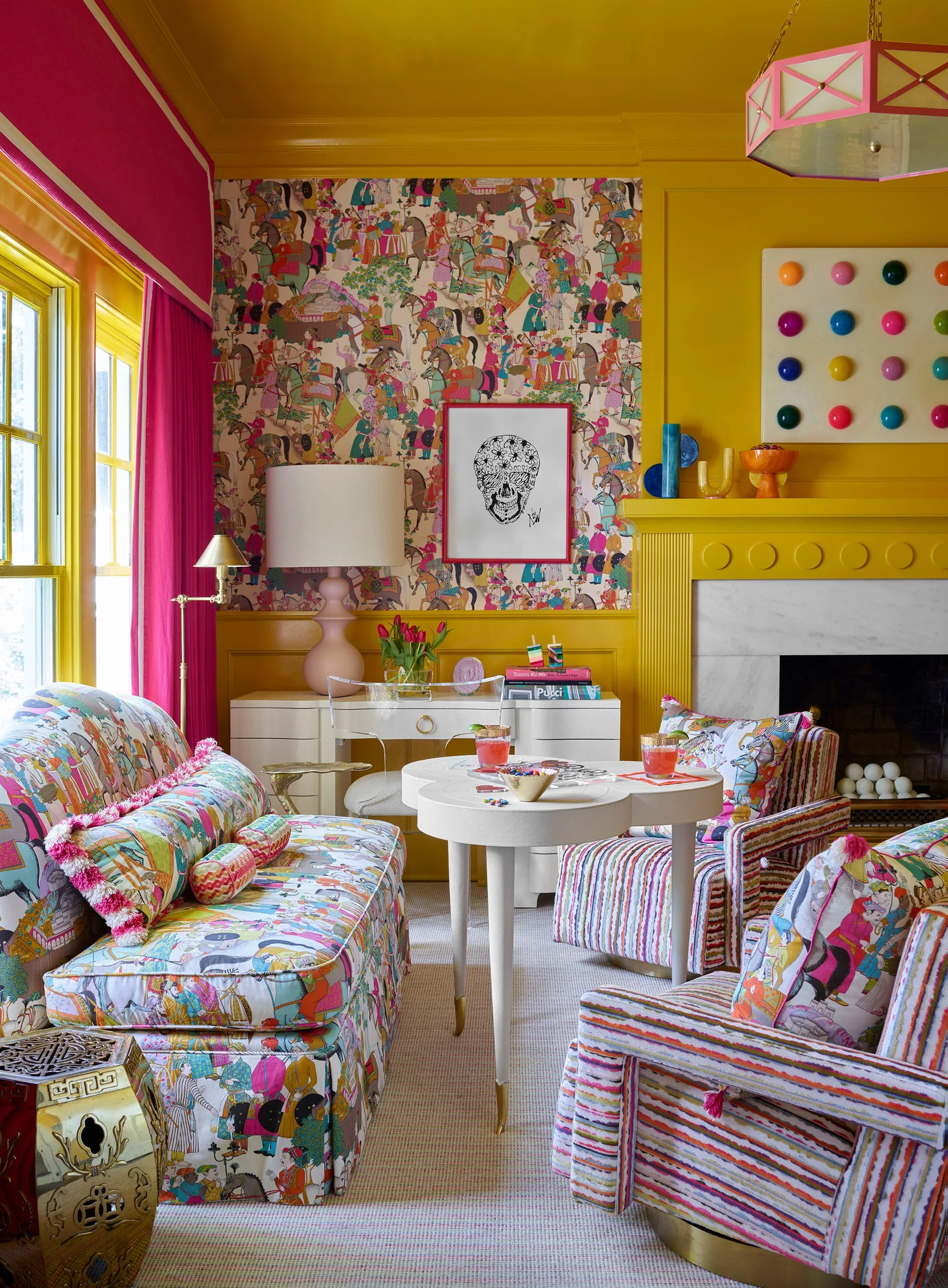 A yellow living room with a patterned sofa matching the wallpaper, striped armchairs, a white lobed coffee table, and a yellow fireplace mantel.