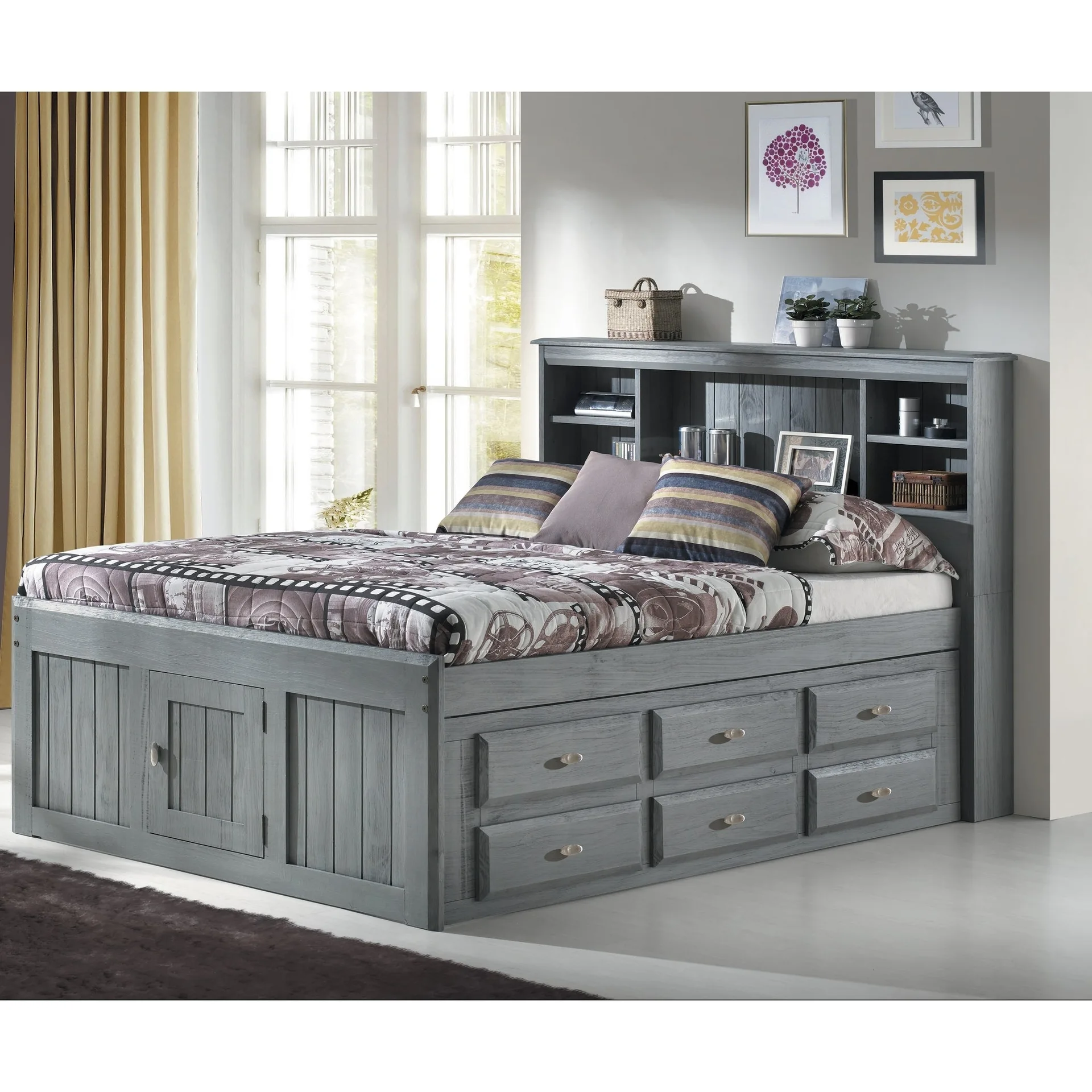 A grey wooden storage bed features drawers built into the base and an integrated bookcase headboard styled with books and decor.