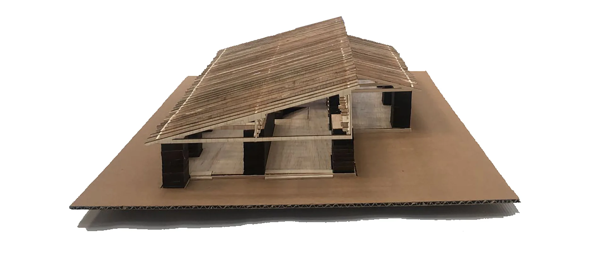 An architectural scale model made of balsa wood and cardboard showcases a structural house design with a sloped roof and dark support columns.