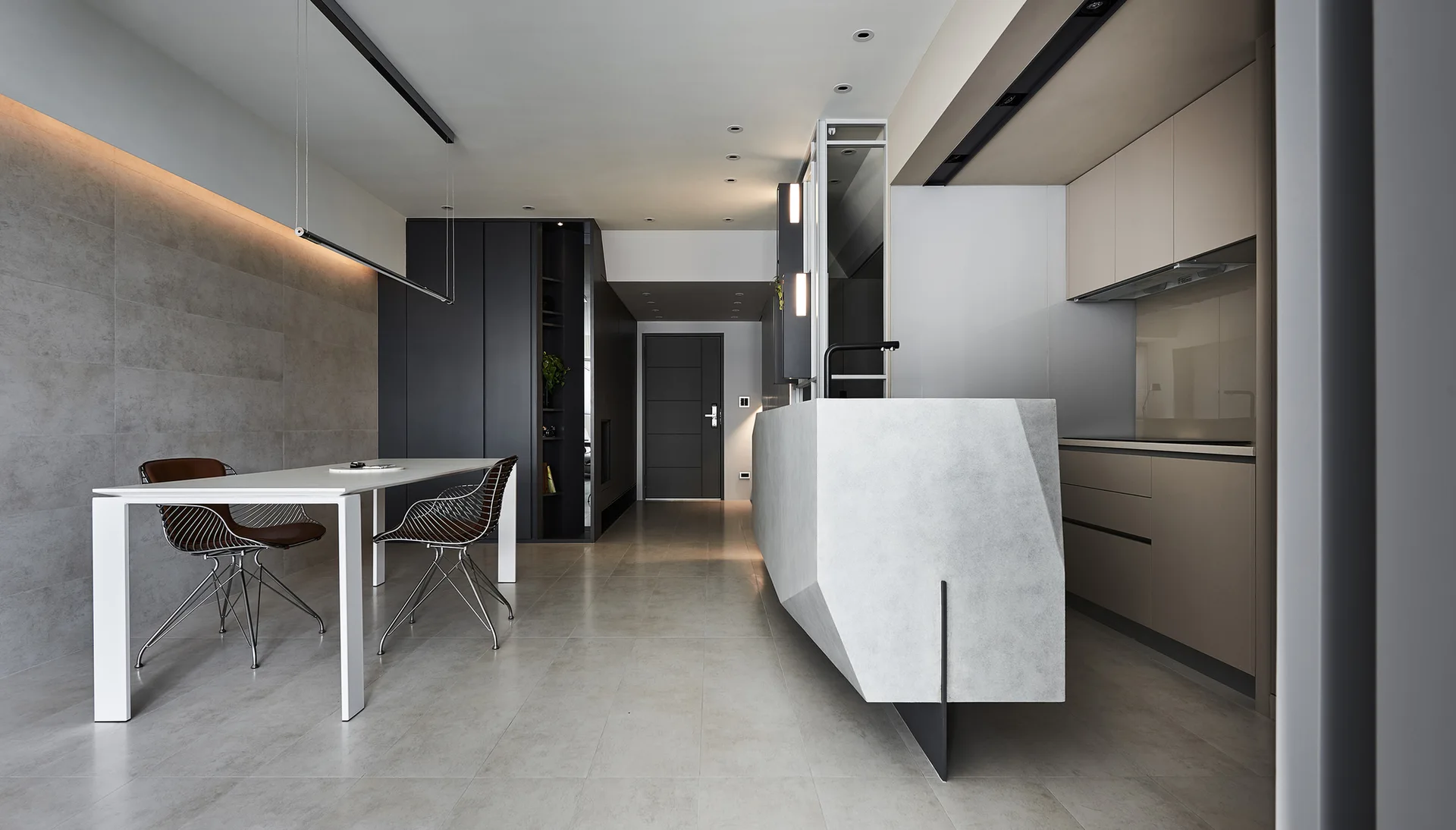 A minimalist modern kitchen and dining space with a geometric stone-like island, wire-frame chairs, and matte beige cabinetry.