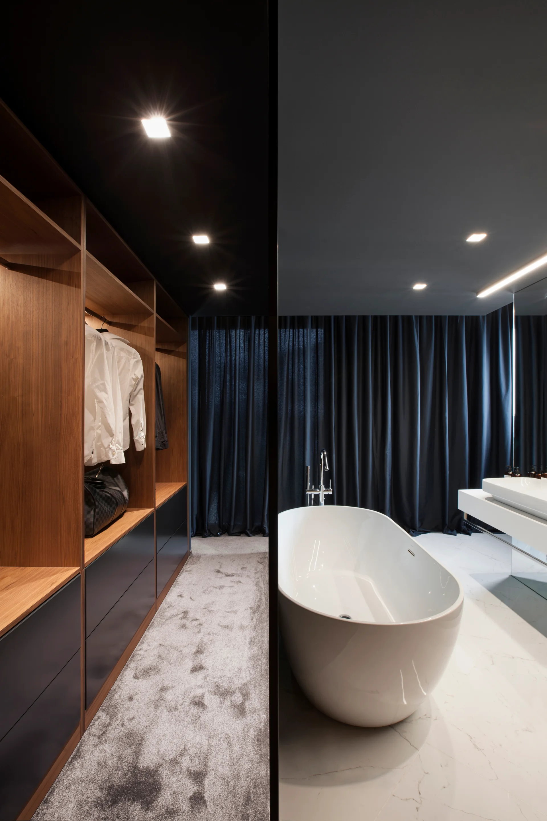A split view of a modern walk-in closet with wood shelving and a bathroom featuring a freestanding white bathtub and white marble tile floors.