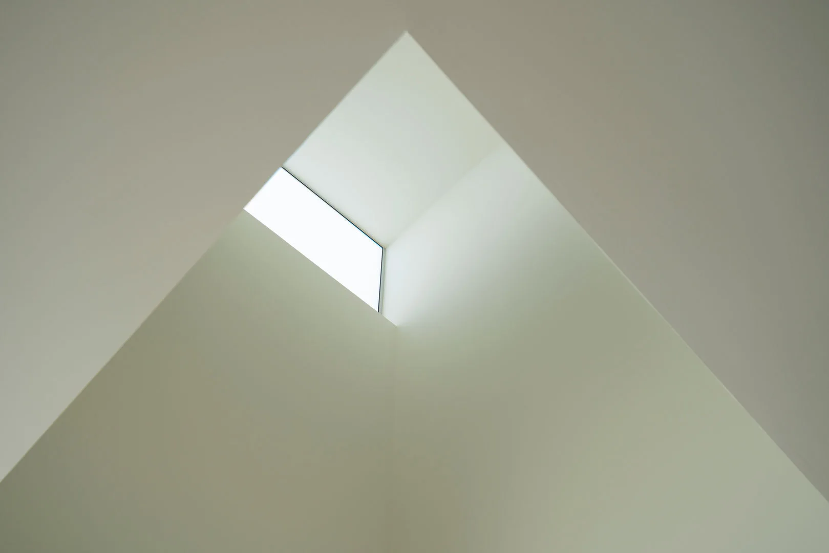 Clean white sloped ceiling featuring a rectangular skylight that brings in bright natural light.