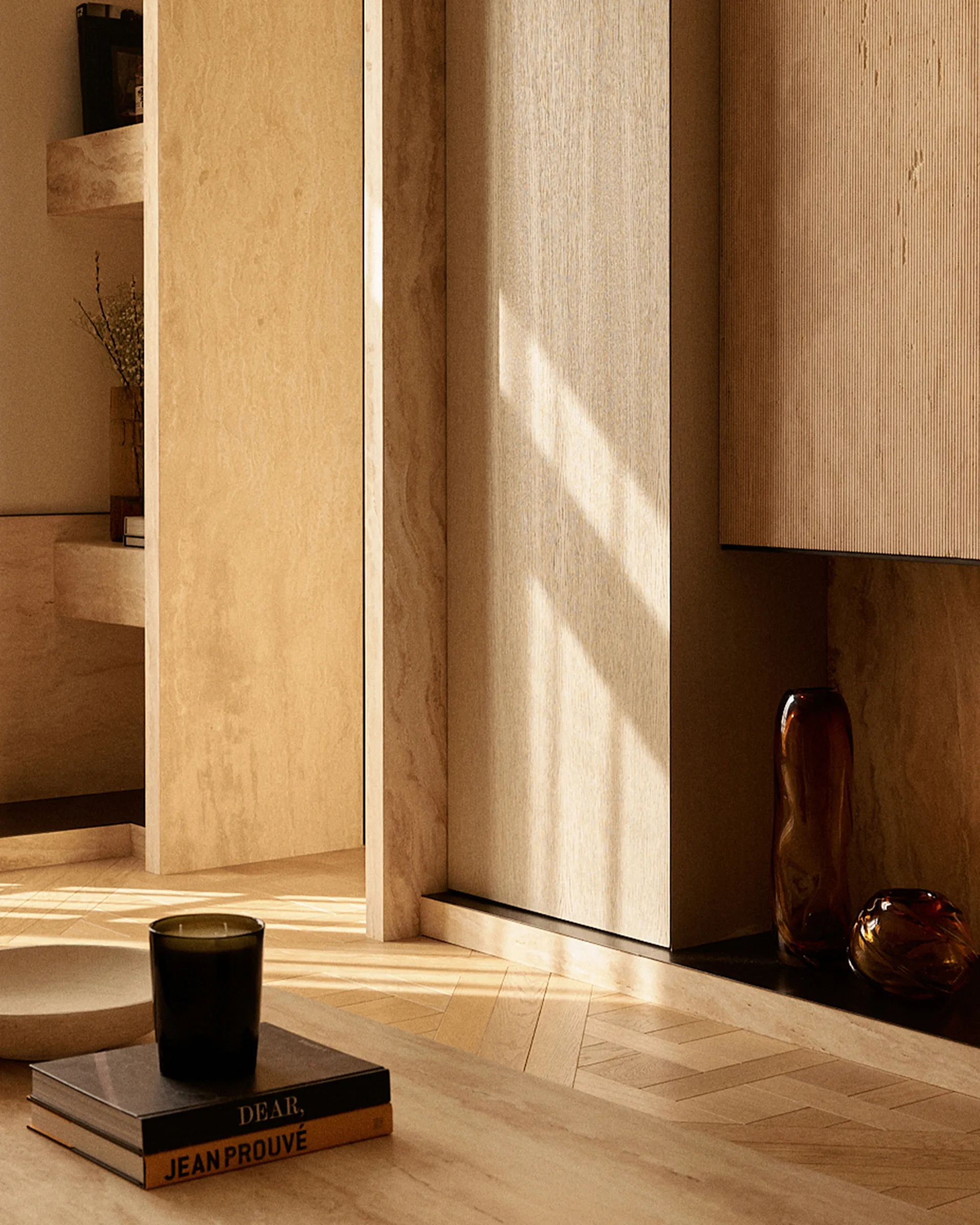 A close-up of a warm interior featuring ribbed wood cabinetry, a herringbone parquet floor, and travertine stone wall panels with built-in shelves.