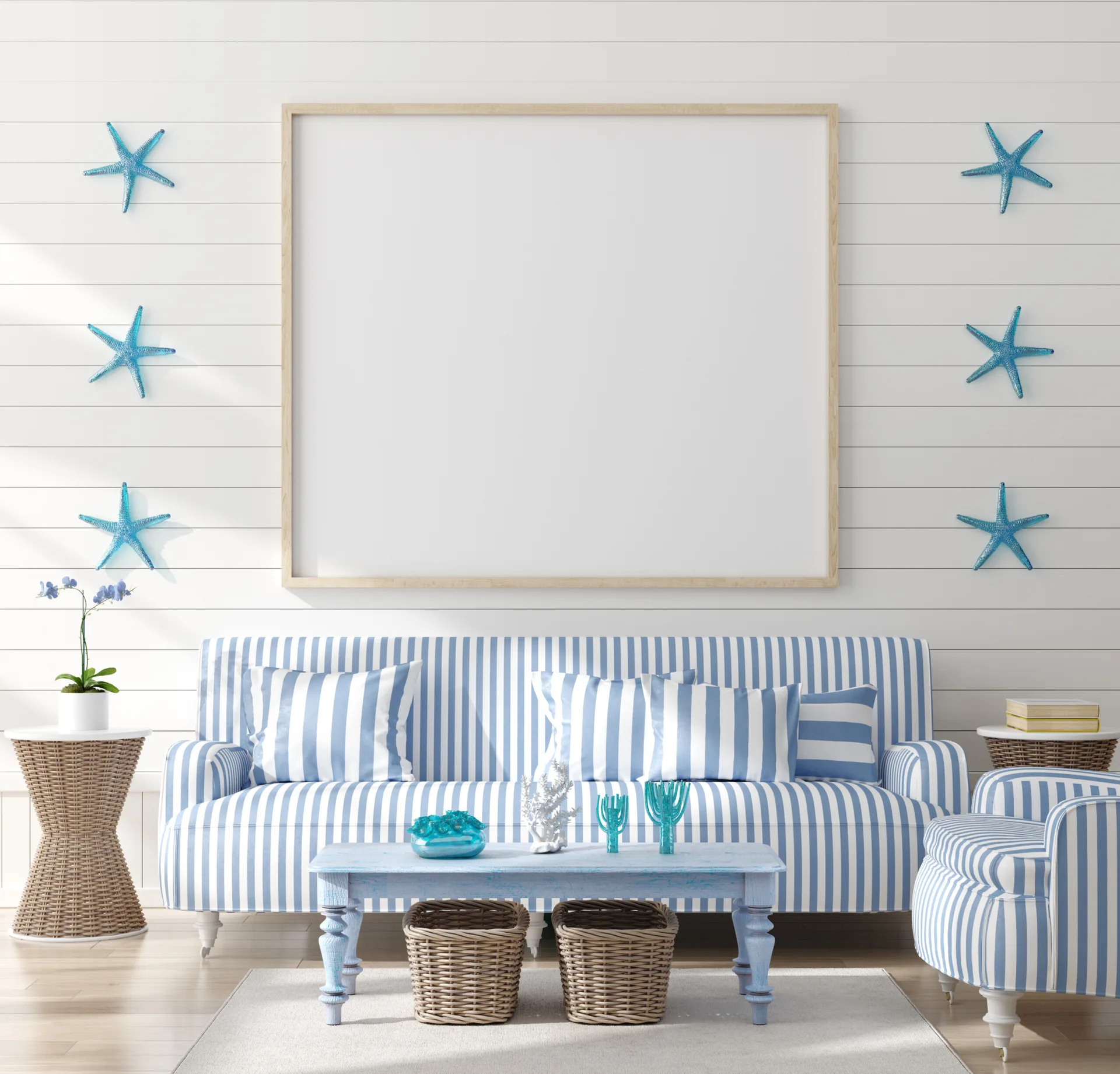 A coastal living room features a blue and white striped sofa, a large empty wood frame, and blue starfish accents on white paneled walls.