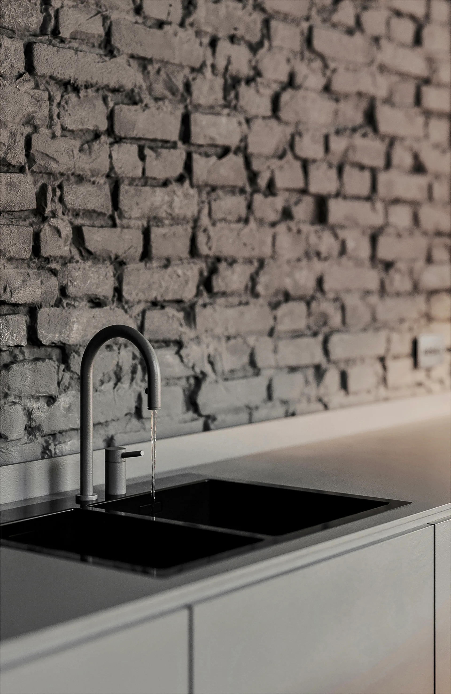 A minimalist matte grey gooseneck faucet pours water into a black double sink set against a textured dark grey exposed brick wall.