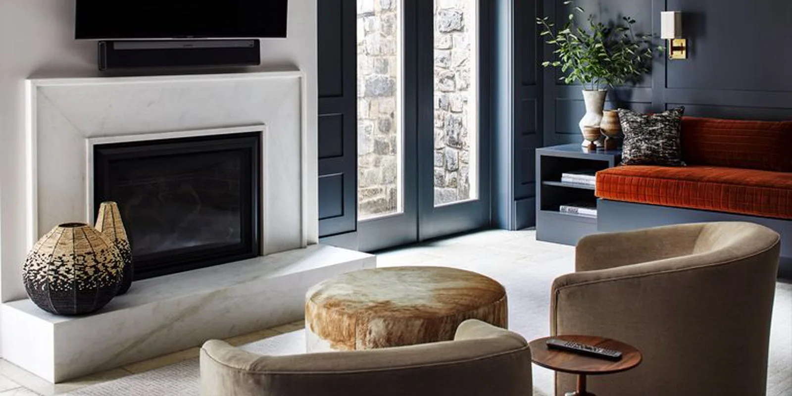 A living room features a white marble fireplace, dark blue paneled walls, and a built-in bench with a burnt orange cushion.