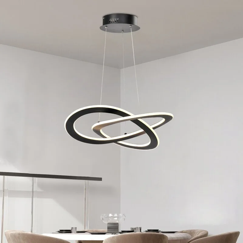A modern black pendant light with overlapping LED rings hangs above a dining table with beige chairs.