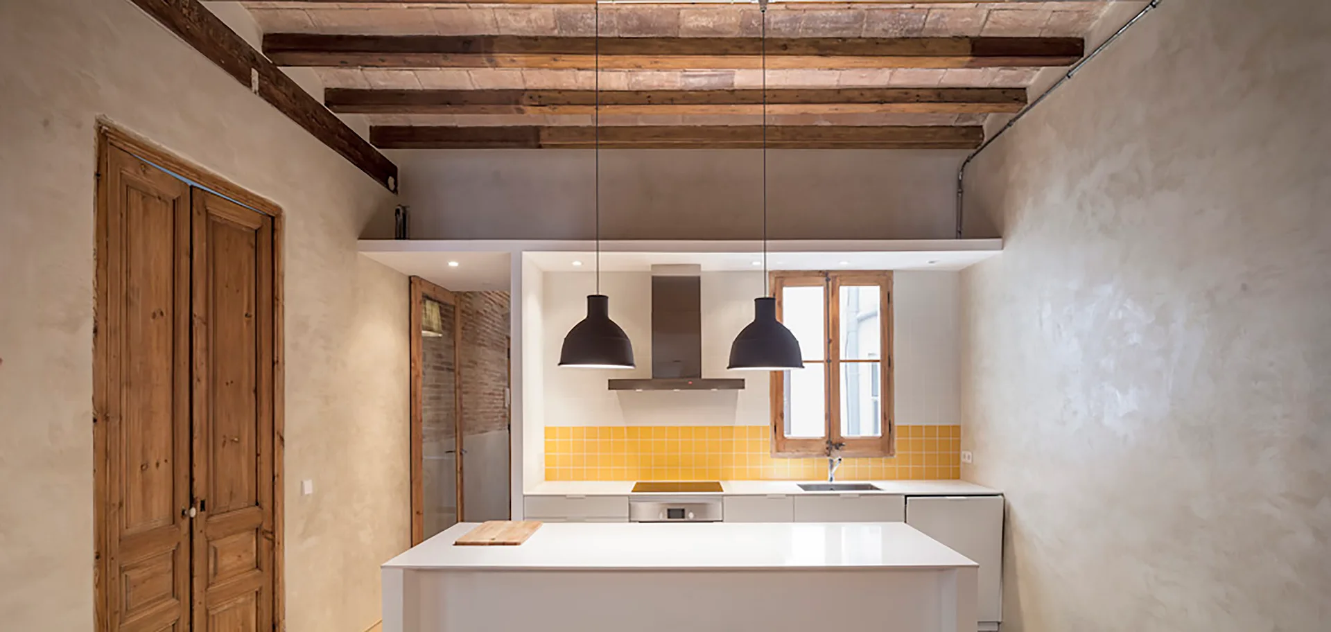 A modern kitchen featuring a white island, a bright yellow tile backsplash, exposed wooden ceiling beams, and plaster walls.