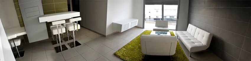 A minimalist living room features white leather sofas on a lime green shag rug next to a modern breakfast bar with white stools.