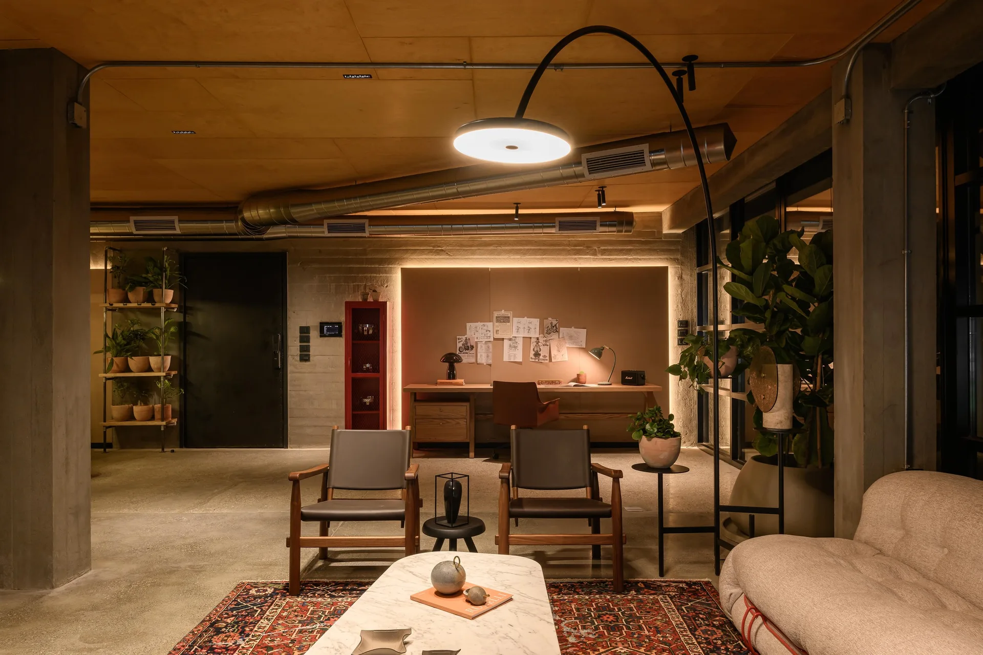 An industrial lounge features two wood-frame leather armchairs, a marble coffee table, raw concrete walls, and a warm wood-plank ceiling.