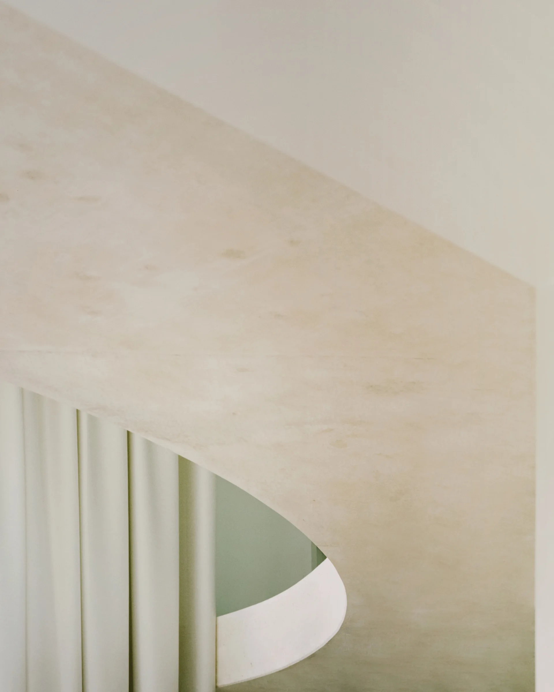 A close-up view of a curved plaster archway in a neutral tone next to soft, pleated off-white drapery.