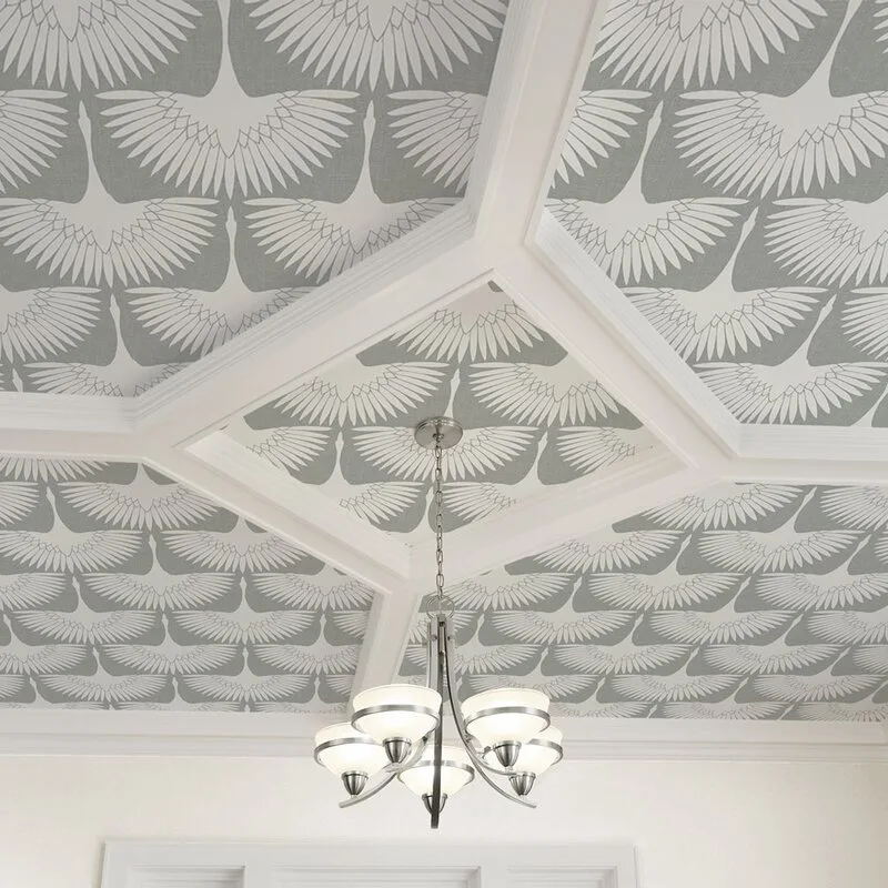 A white coffered ceiling with recessed panels featuring grey and white crane patterned wallpaper, with a five-light metal chandelier hanging from the center.