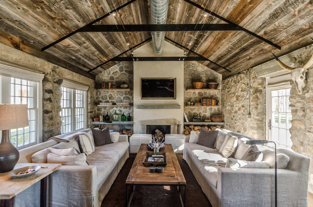 Living room with stone walls and raw wood slatted ceiling&nbsp;