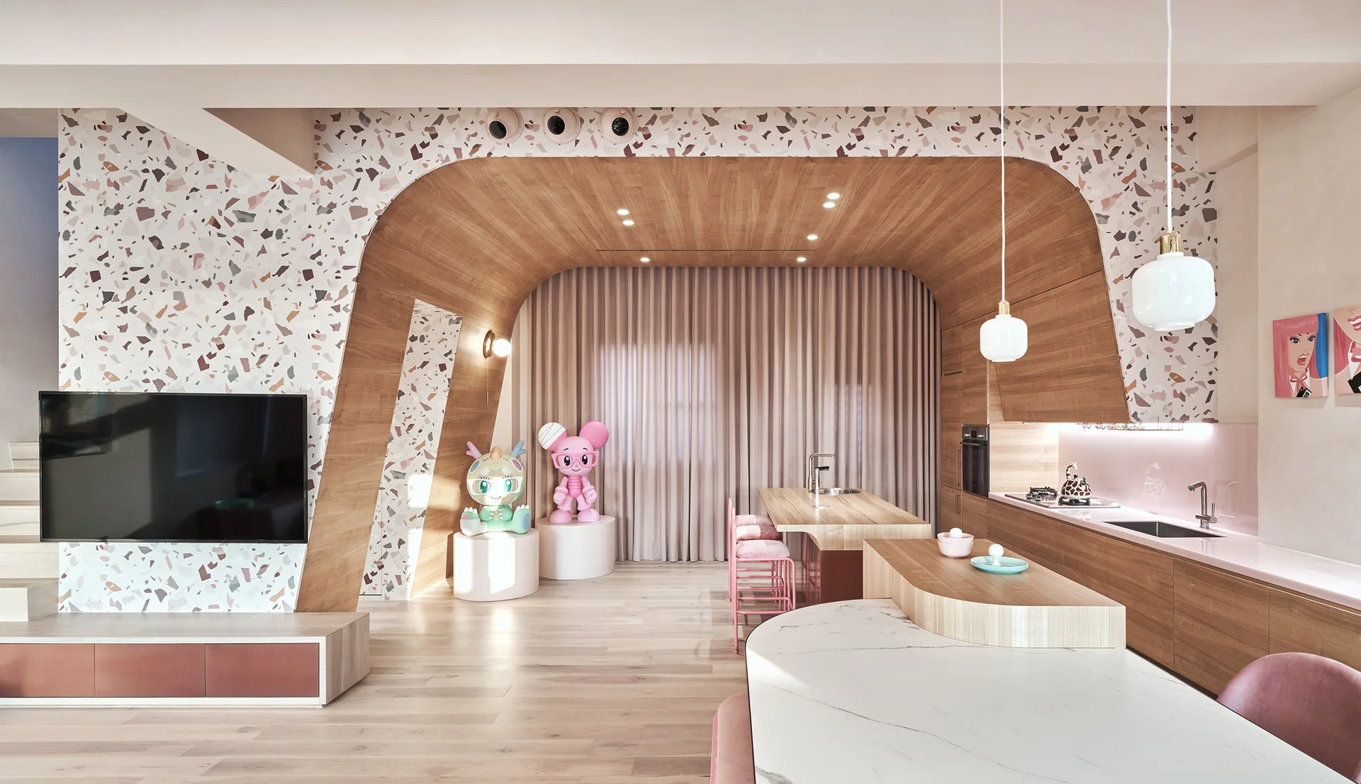 A modern kitchen featuring a curved wooden archway, a pink backsplash, pink barstools, and walls in a colorful terrazzo pattern.