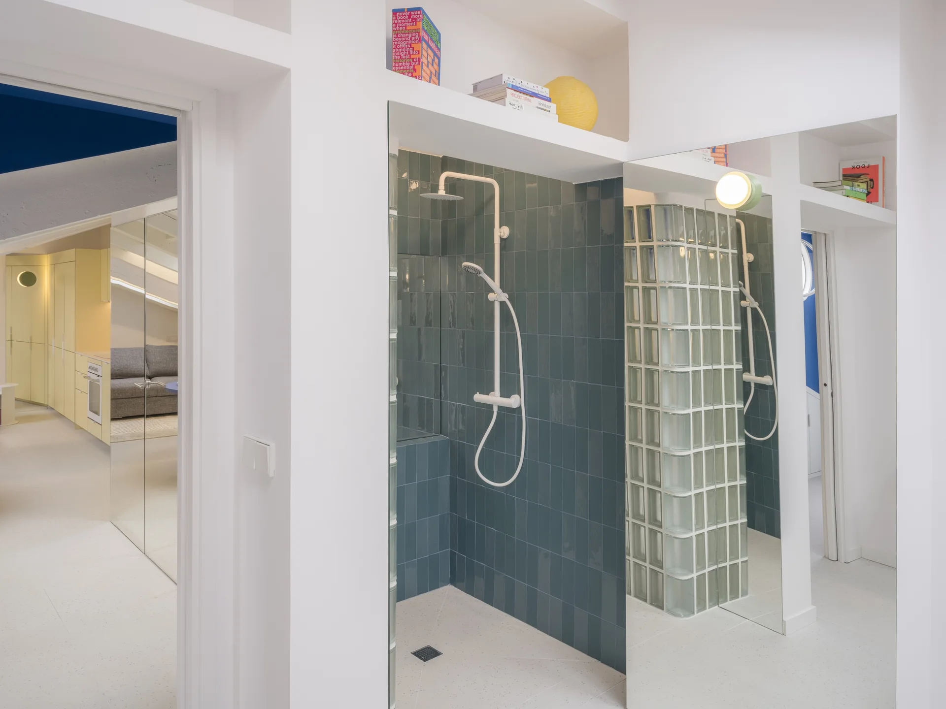 A modern bathroom features a tiled shower stall with a glass block partition and large wall mirrors reflecting the space.
