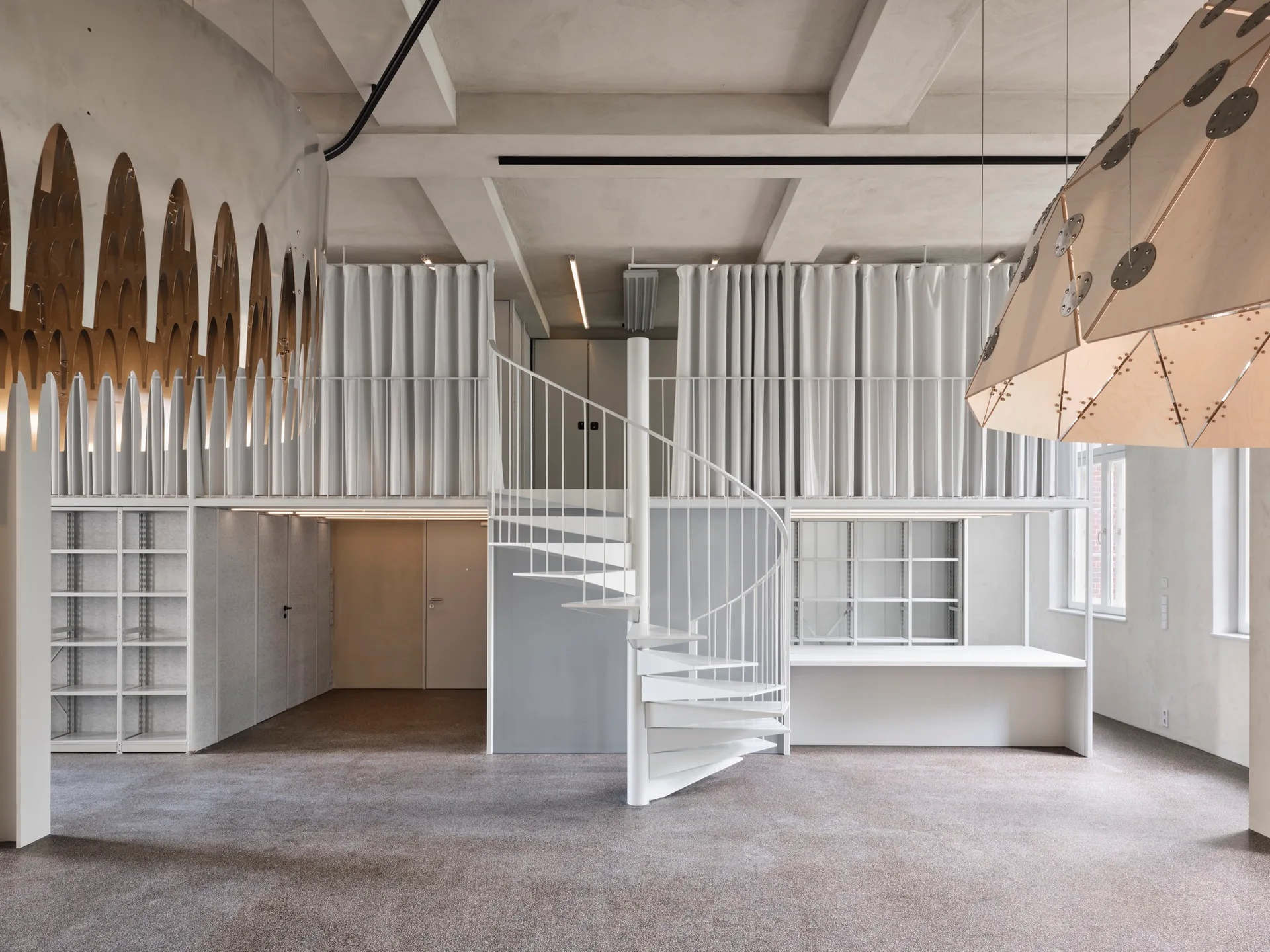 A central white metal spiral staircase connects a ground floor to a mezzanine level partitioned by white fabric curtains under a concrete ceiling.