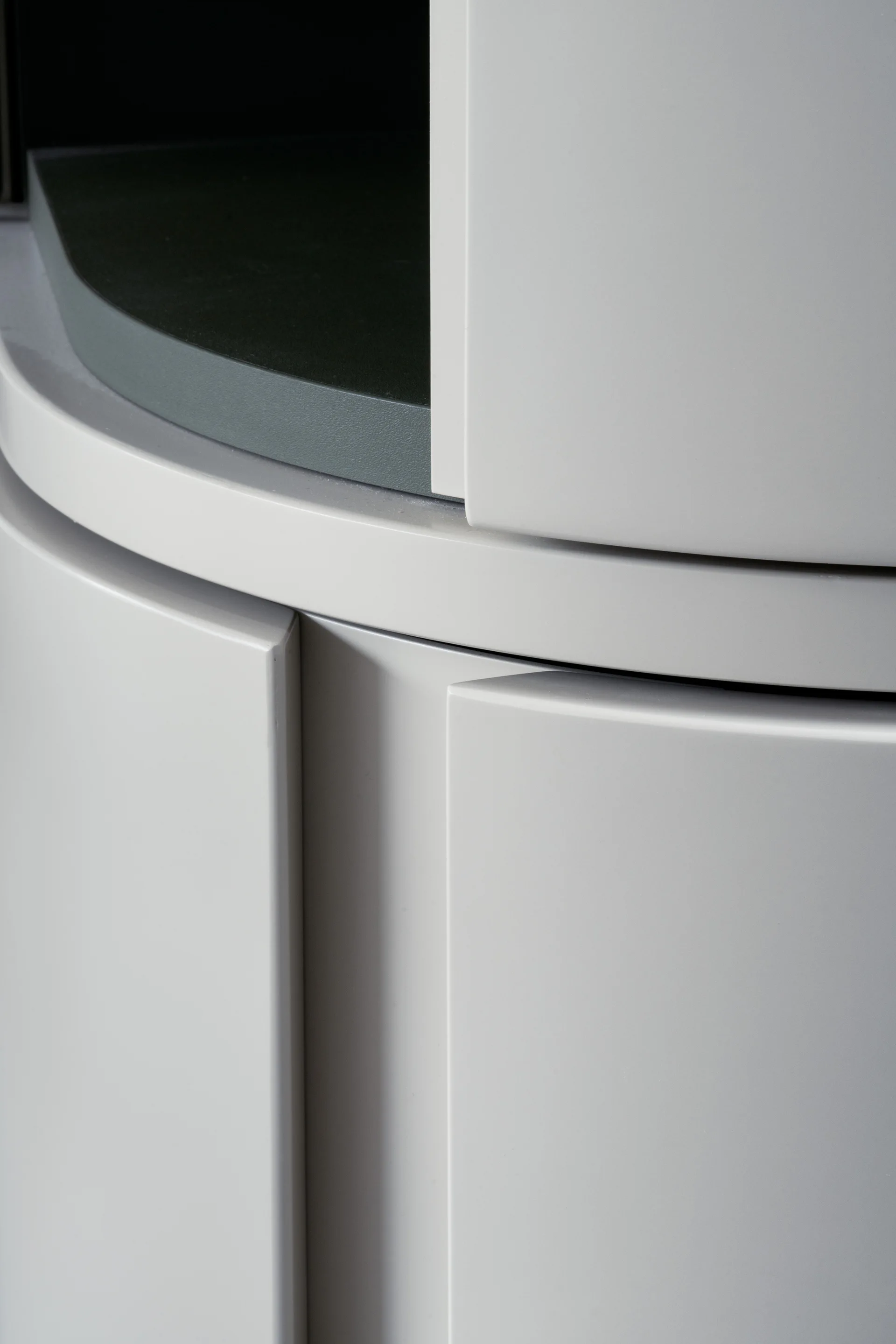 Close-up of custom light grey curved cabinet doors with a matte finish, revealing a dark grey interior shelf.