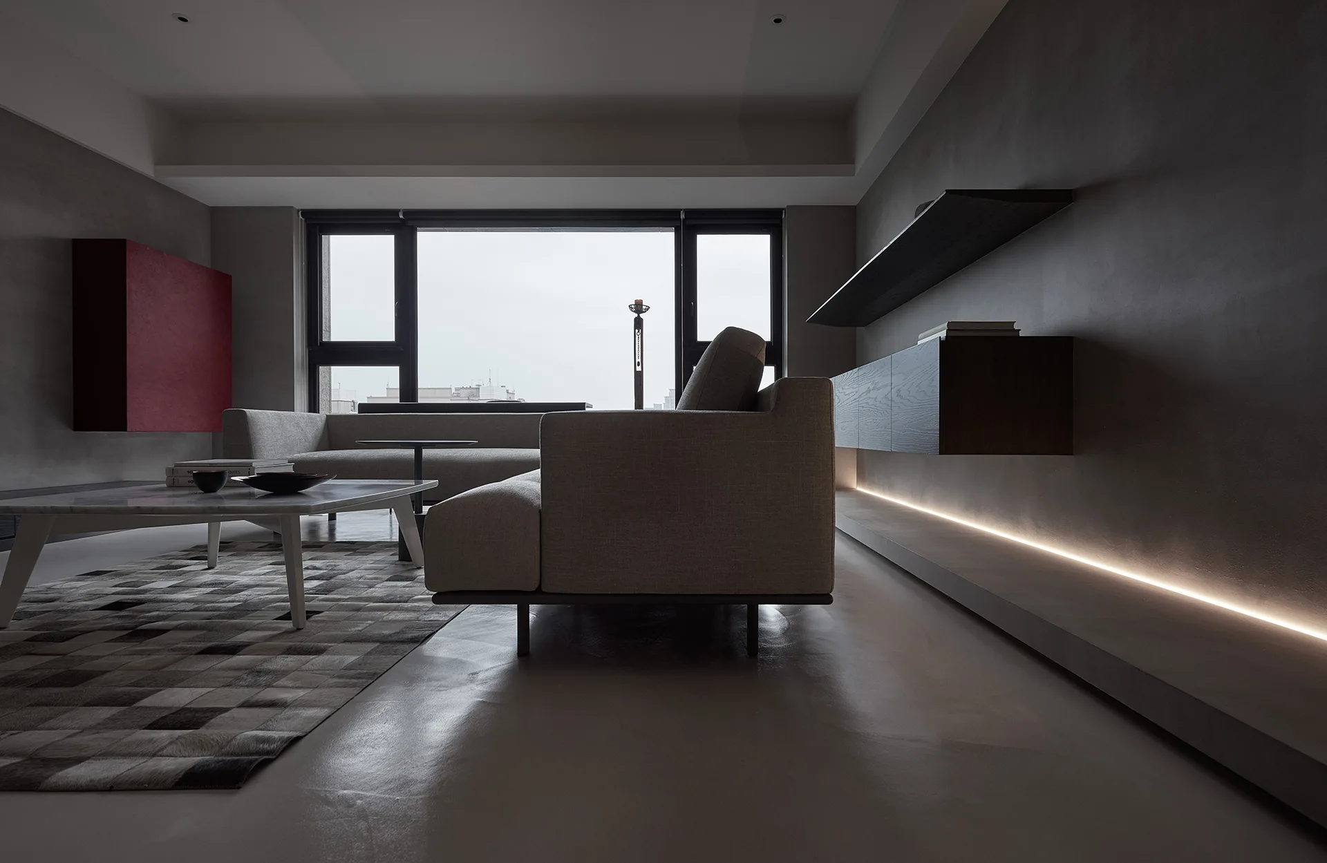 A minimalist living room features a grey sofa, a checkered rug, a marble coffee table, and a floating dark wood cabinet with linear floor lighting.