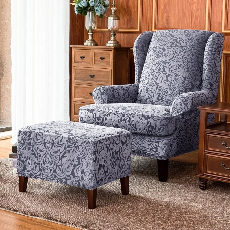 A blue and grey damask patterned wingback armchair and matching ottoman sit on a brown woven rug in front of warm wood-paneled walls.