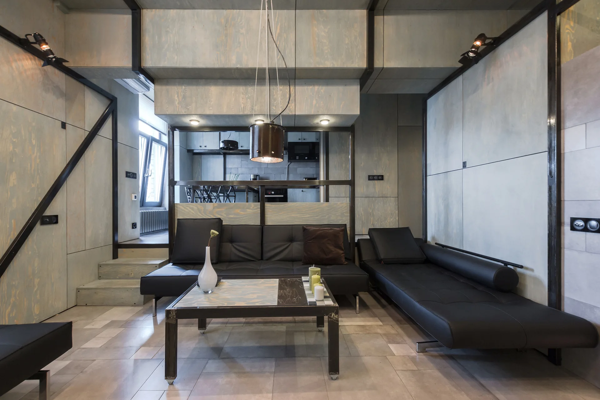 A modern living room features light plywood wall paneling, a low-profile black sectional sofa, and a matching coffee table.