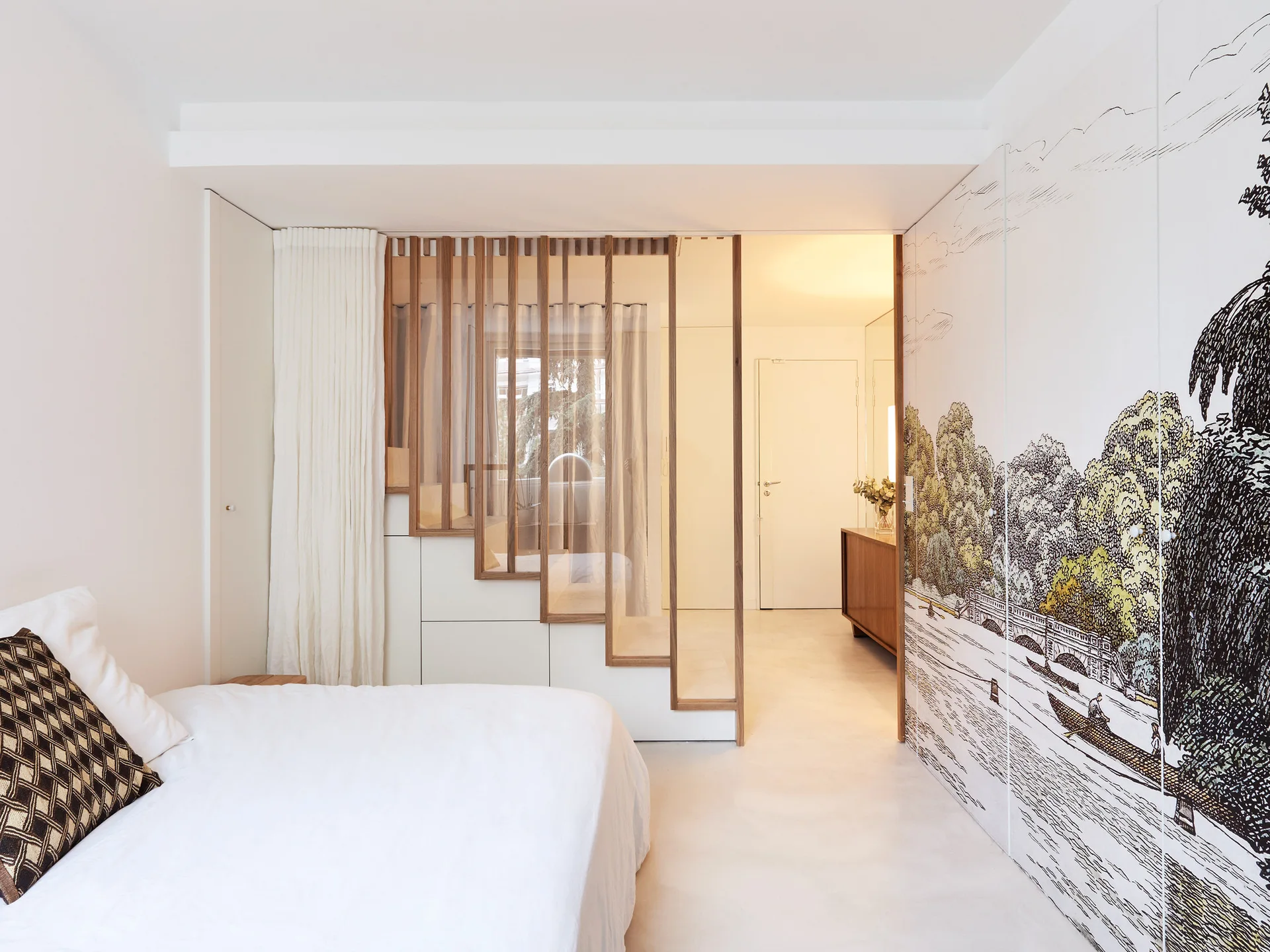 A minimalist bedroom featuring a bed with white linen, a stepped wooden slat partition screen, and wardrobe doors with a detailed landscape illustration.