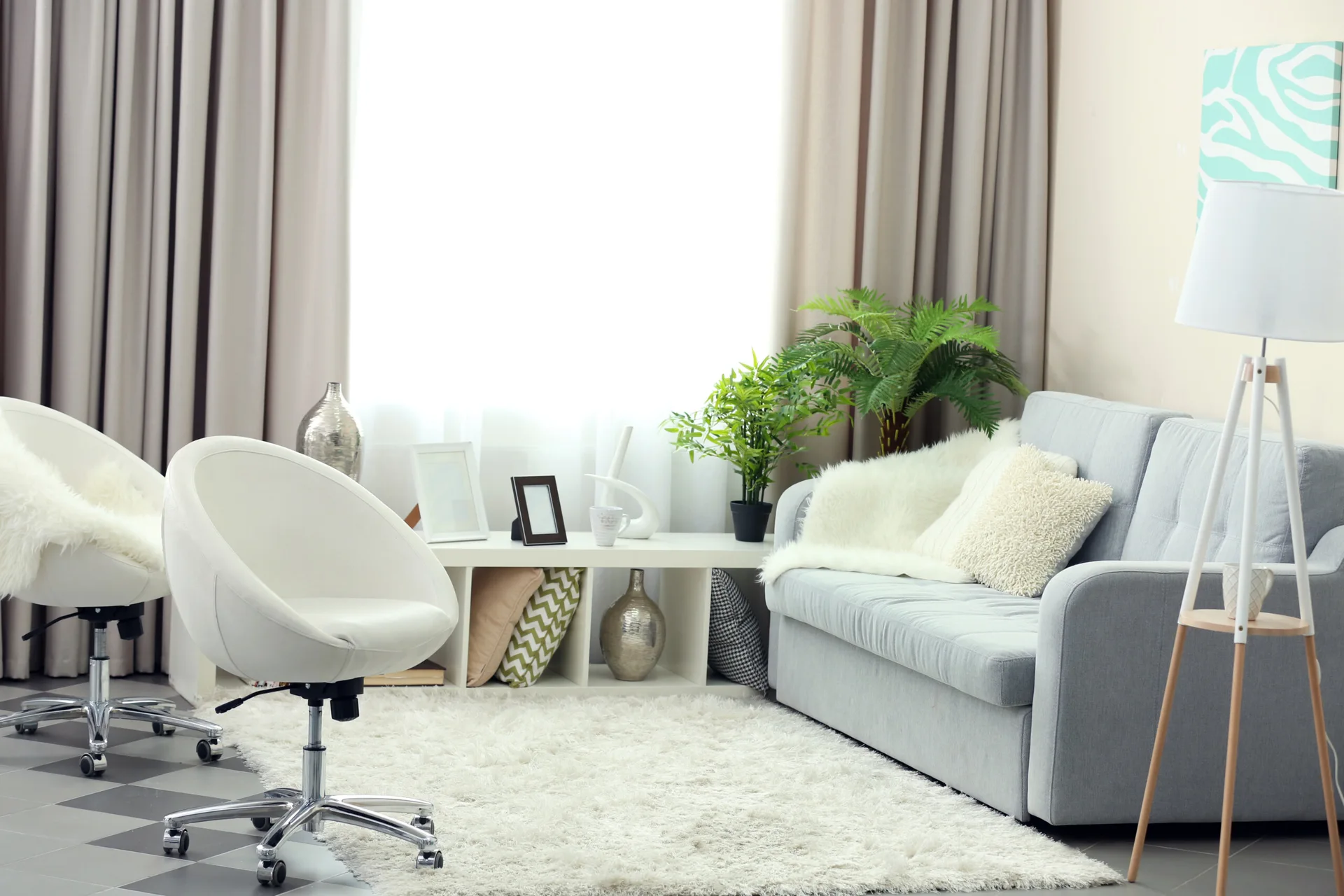 A light grey sofa and white swivel chairs are arranged around a low white shelf on a plush shag rug.