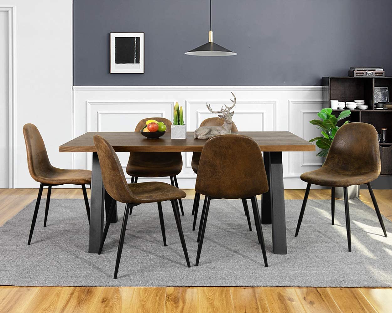A dining room features a wooden table, brown upholstered chairs, a grey rug, and a two-toned wall with white wainscoting.