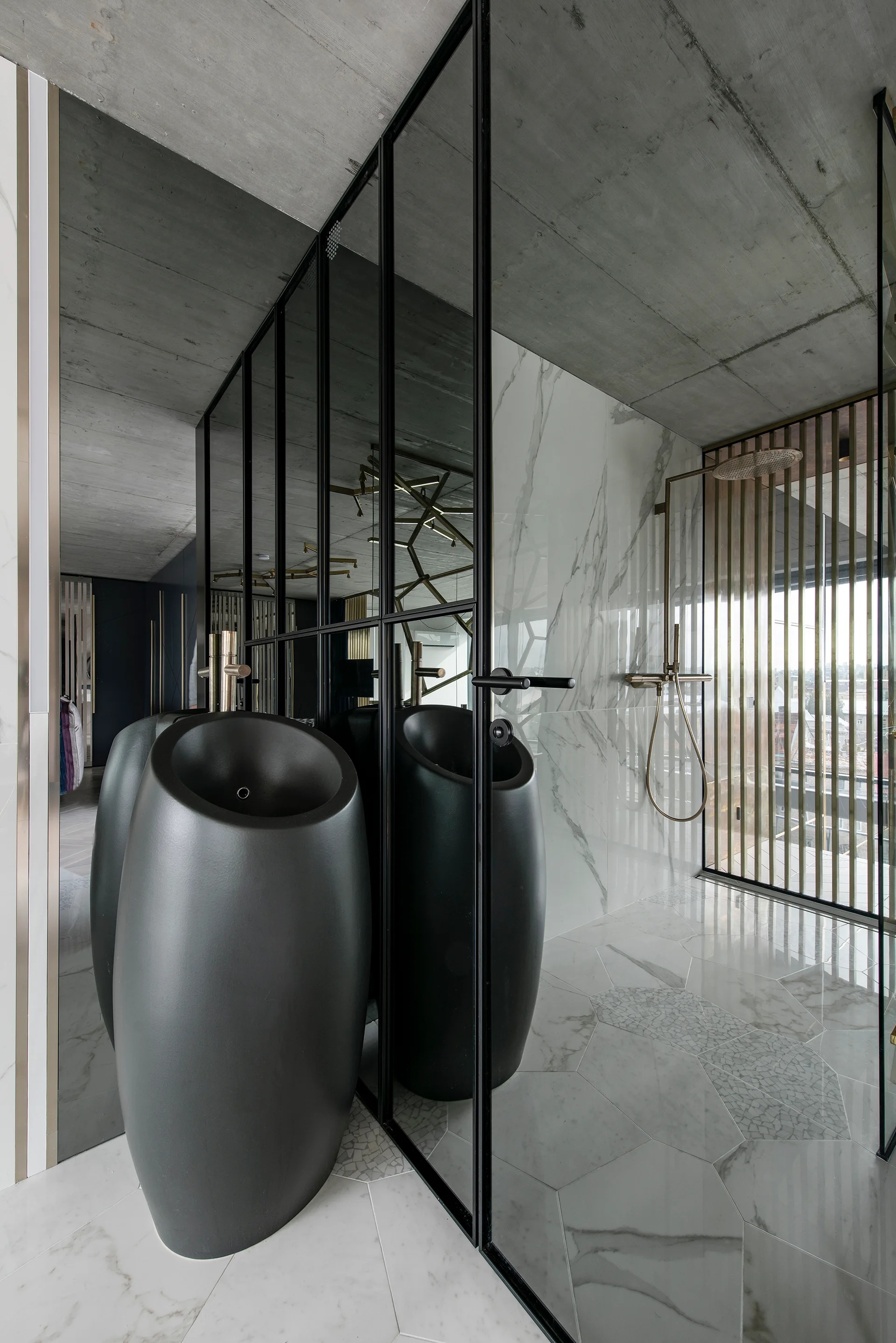 A modern bathroom showcases a curved black pedestal sink, white marble floor tiles, a black-framed glass wall, and an exposed concrete ceiling.