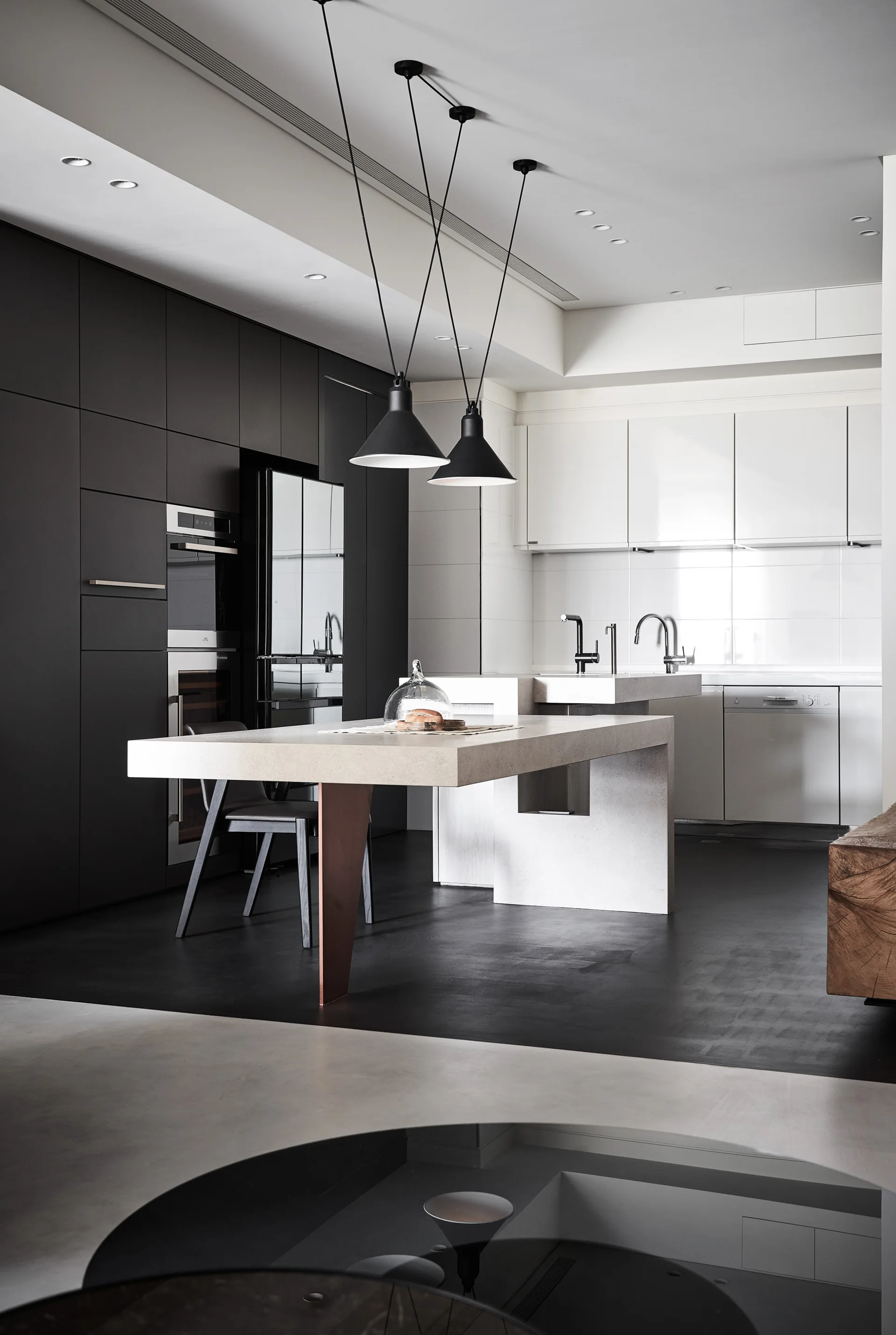 A modern kitchen featuring tall matte black cabinetry, glossy white upper cabinets, a stone island with a metallic support leg, and black pendant lights.