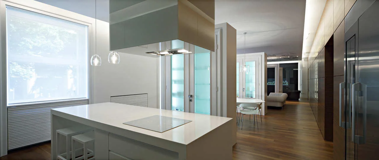 A modern kitchen featuring a white central island, dark wood cabinetry, hardwood floors, and frosted glass doors leading to a dining area.